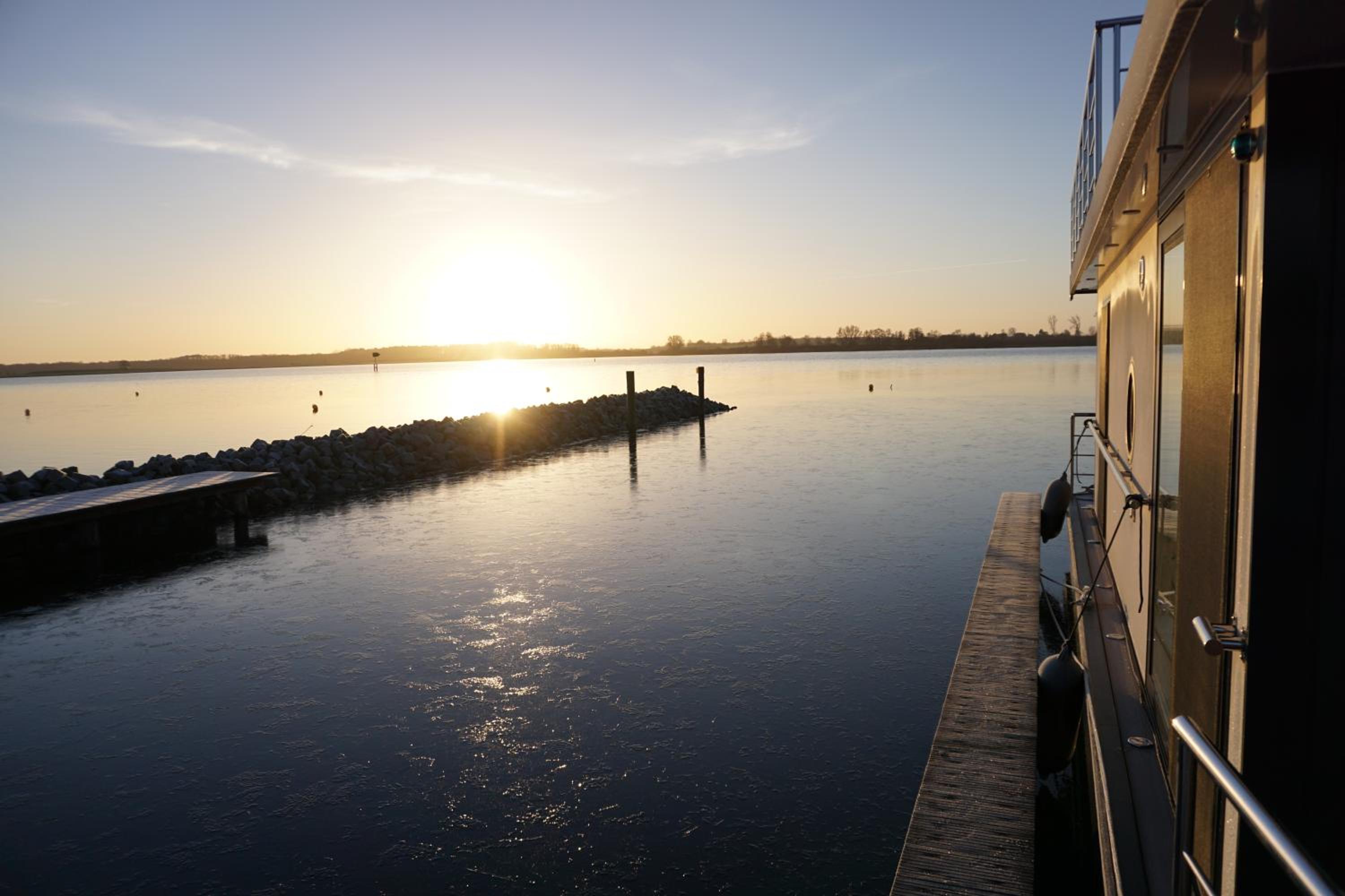 Modernes festliegendes Hausboot mit großzügiger Dachterrasse und Ruderboot