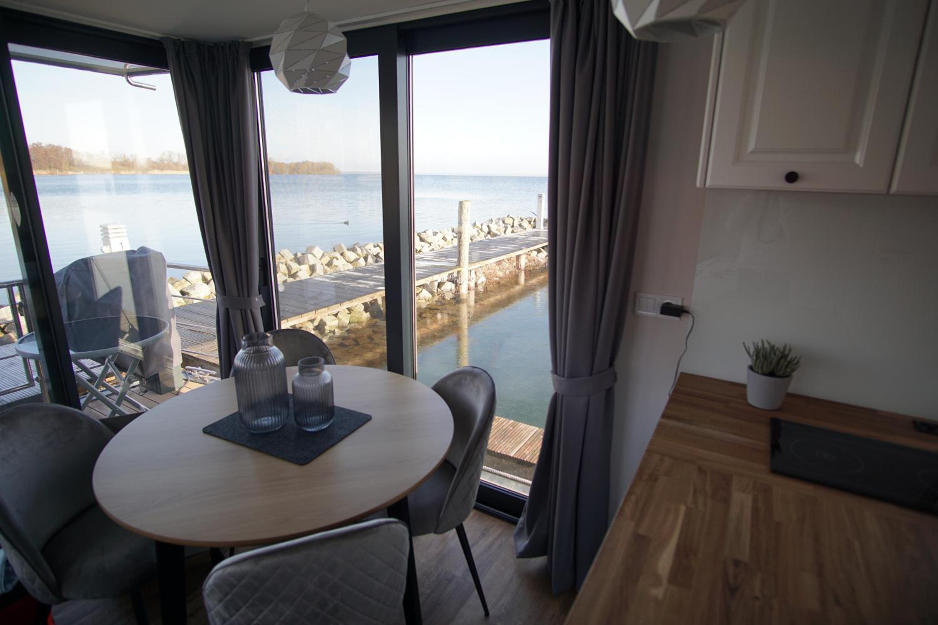 Modernes festliegendes Hausboot mit großzügiger Dachterrasse und Ruderboot