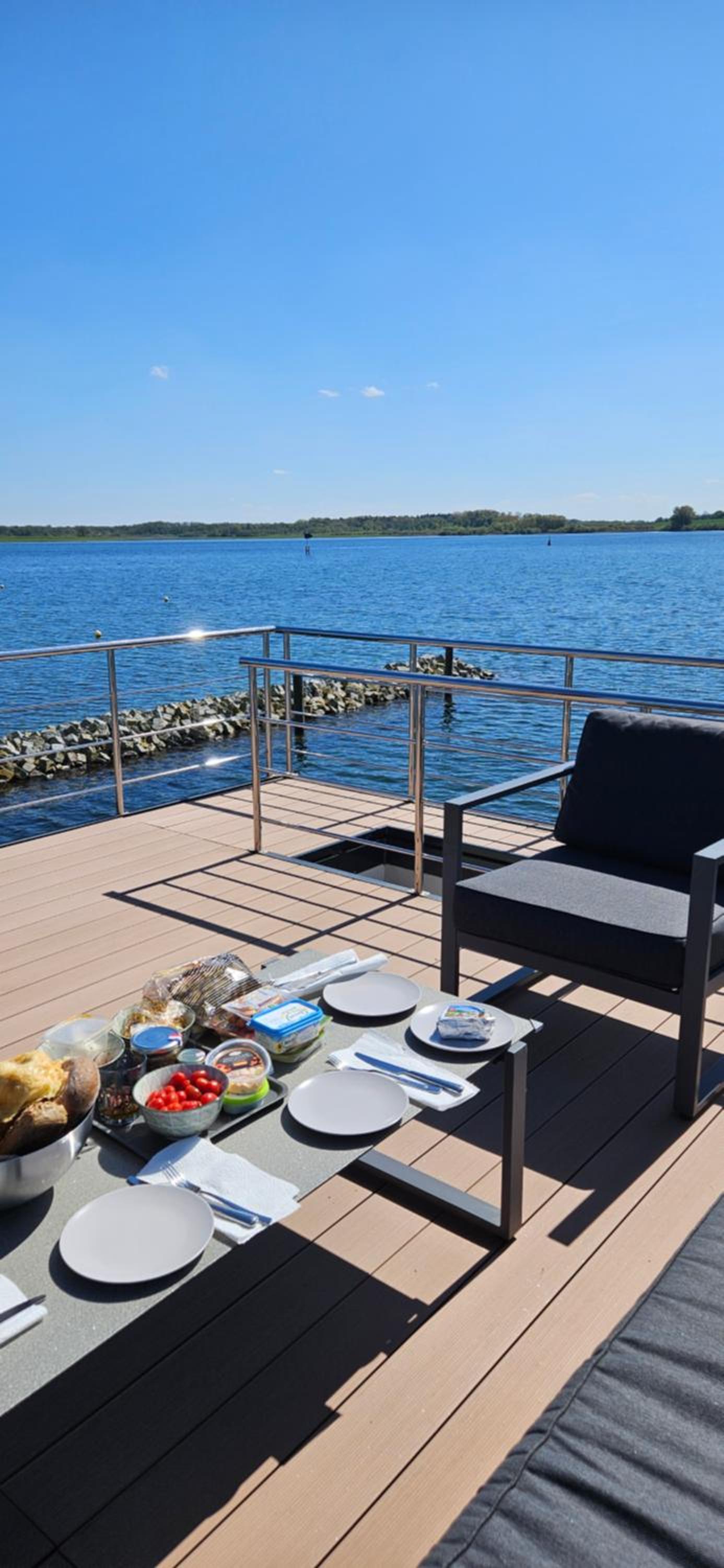 Modernes festliegendes Hausboot mit großzügiger Dachterrasse und Ruderboot