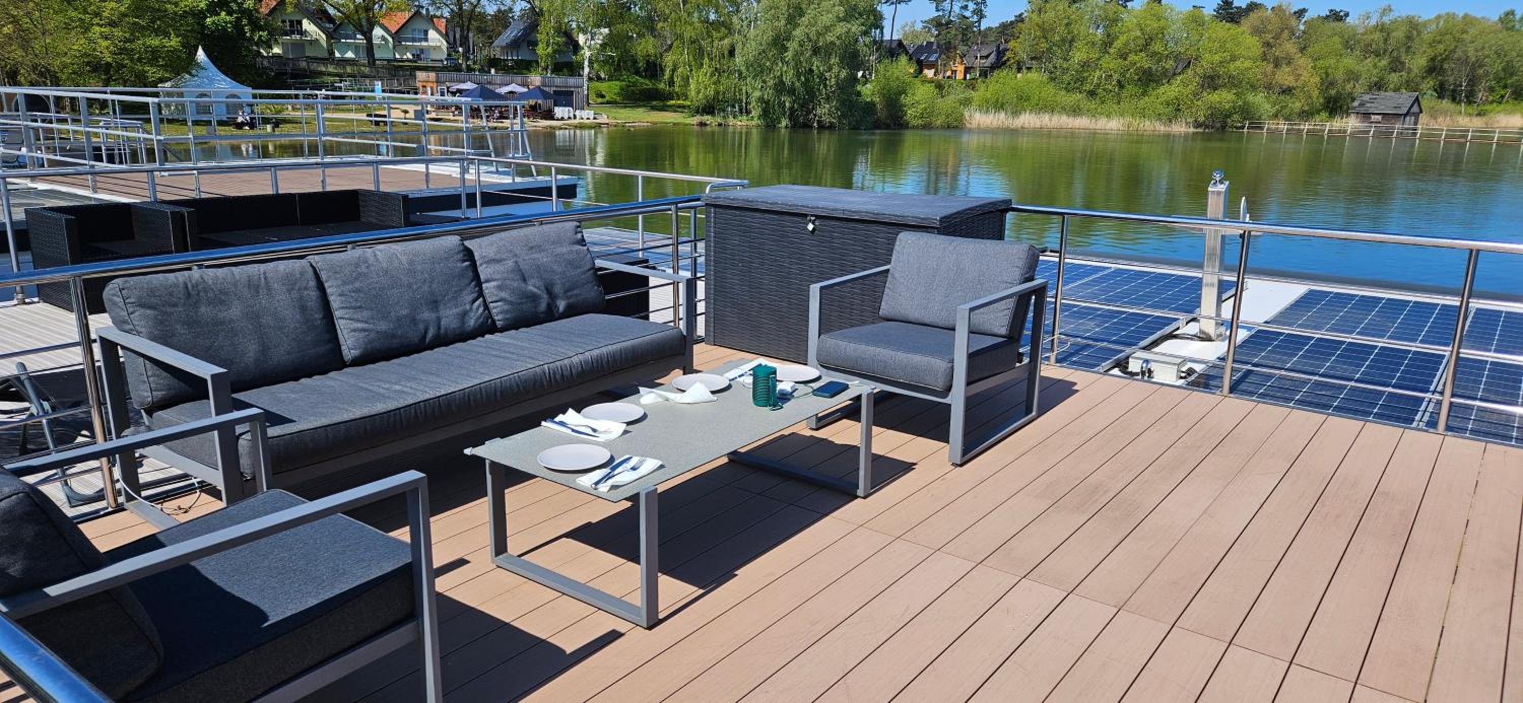 Modernes festliegendes Hausboot mit großzügiger Dachterrasse und Ruderboot