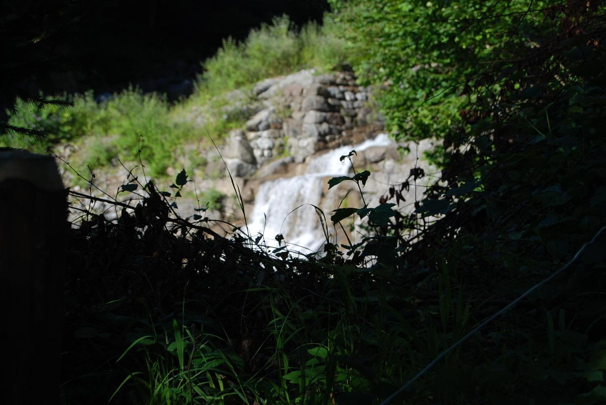 Bergbauernhaus an Wasserfall und Waldrand