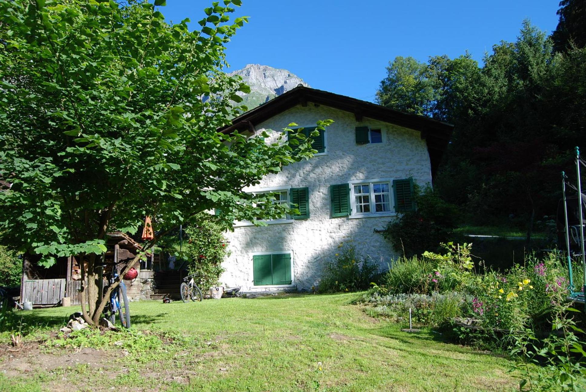 Bergbauernhaus an Wasserfall und Waldrand