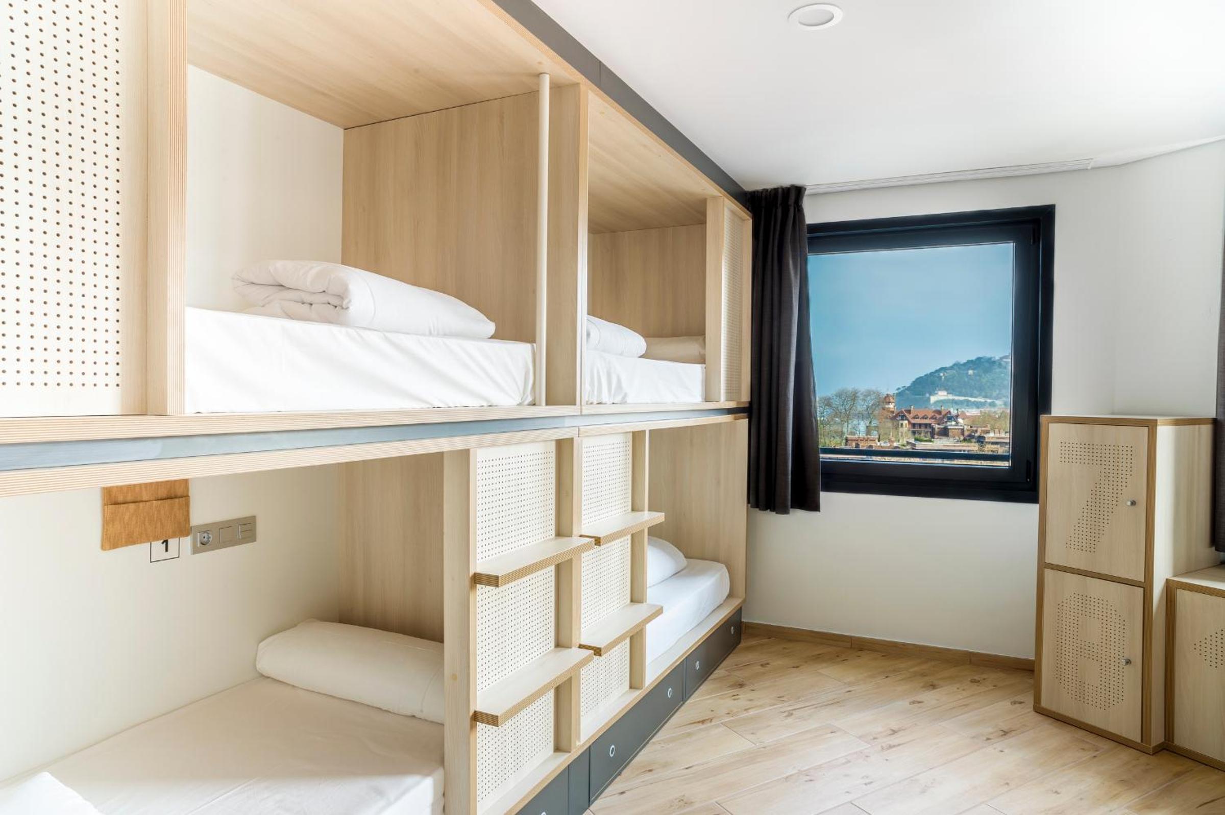 Cama en dormitorio compartido mixto de 8 camas con baño privado.