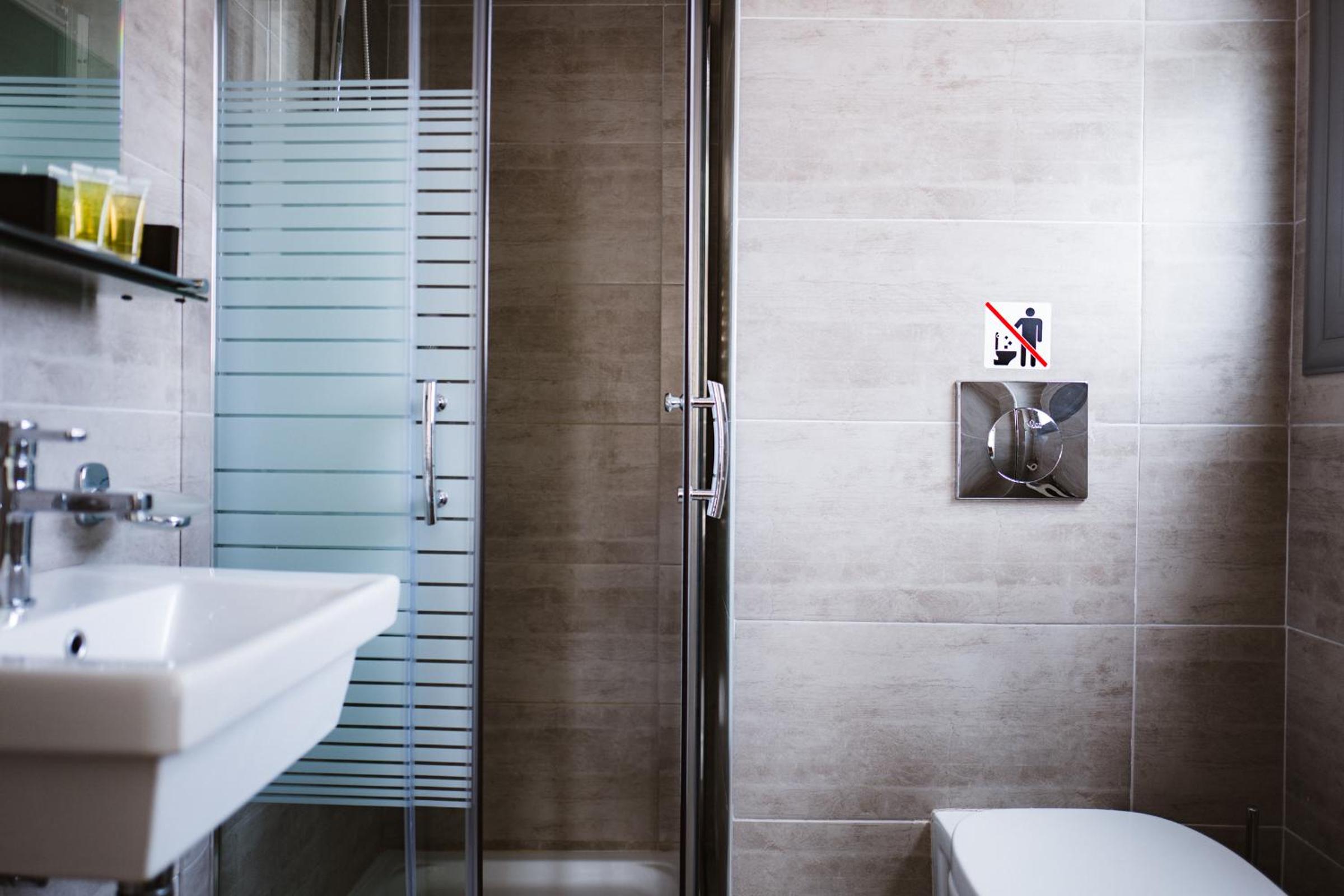 Bathroom with a white sink, glass shower enclosure, and beige tiled walls.