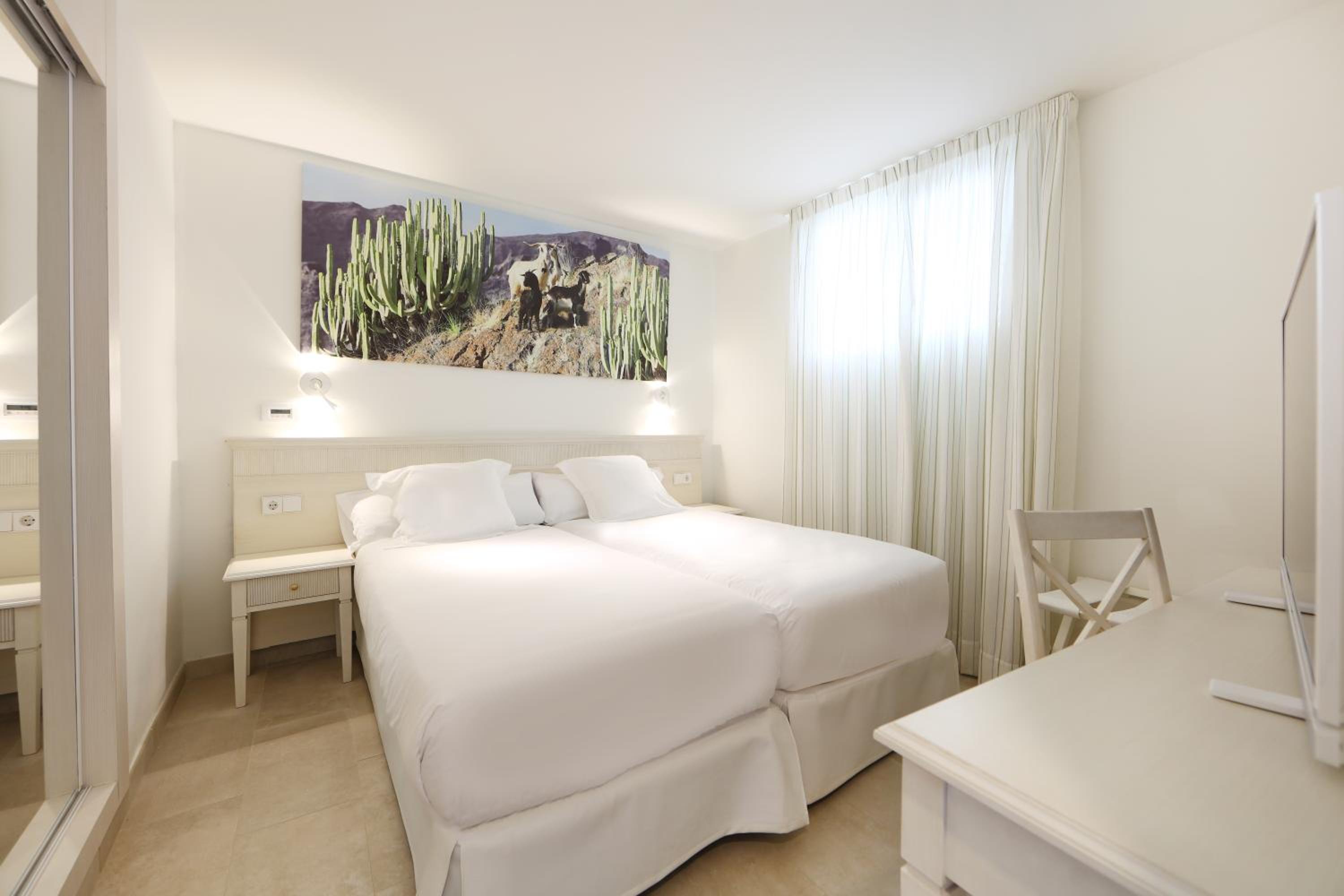 white bedroom with two beds and a painting on the wall