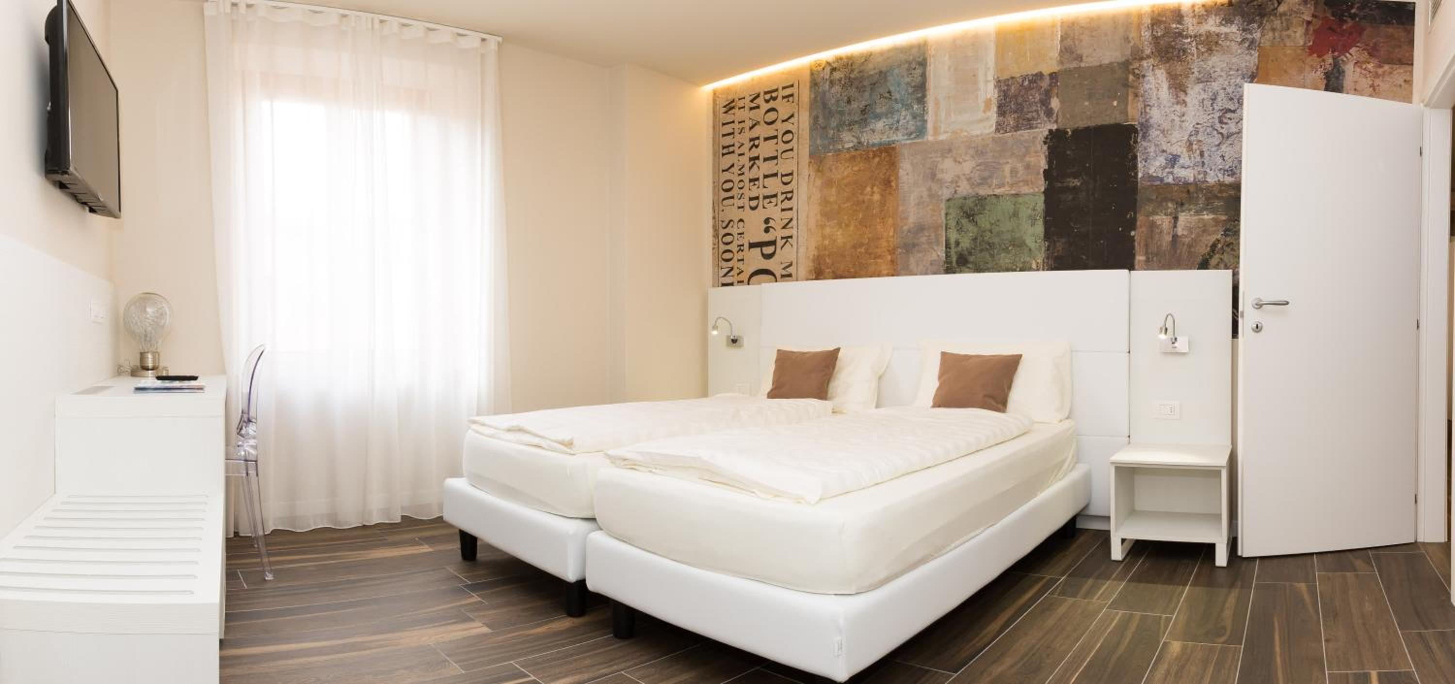 Modern white bedroom with large bed, patchwork accent wall and wood-look floor