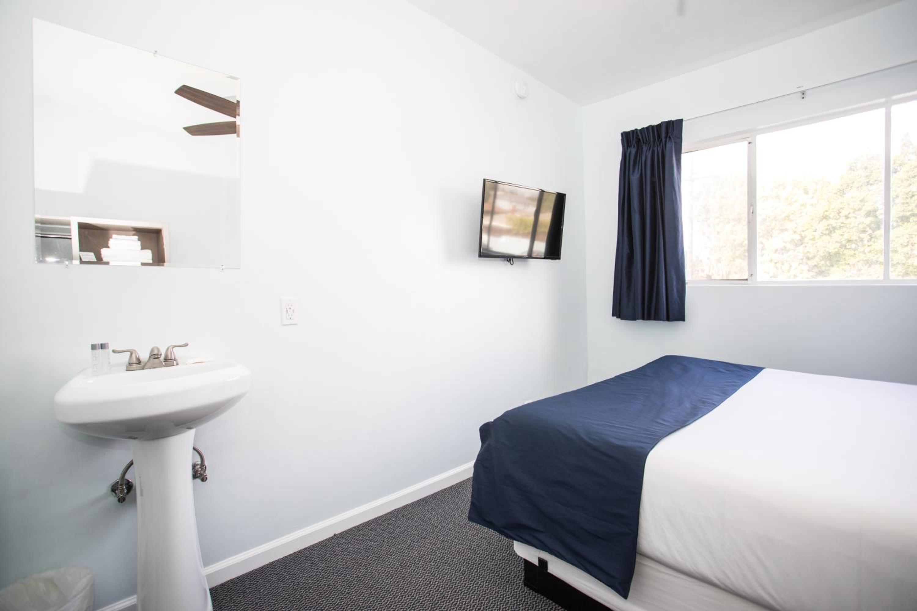 Bedroom with bed, sink, and TV