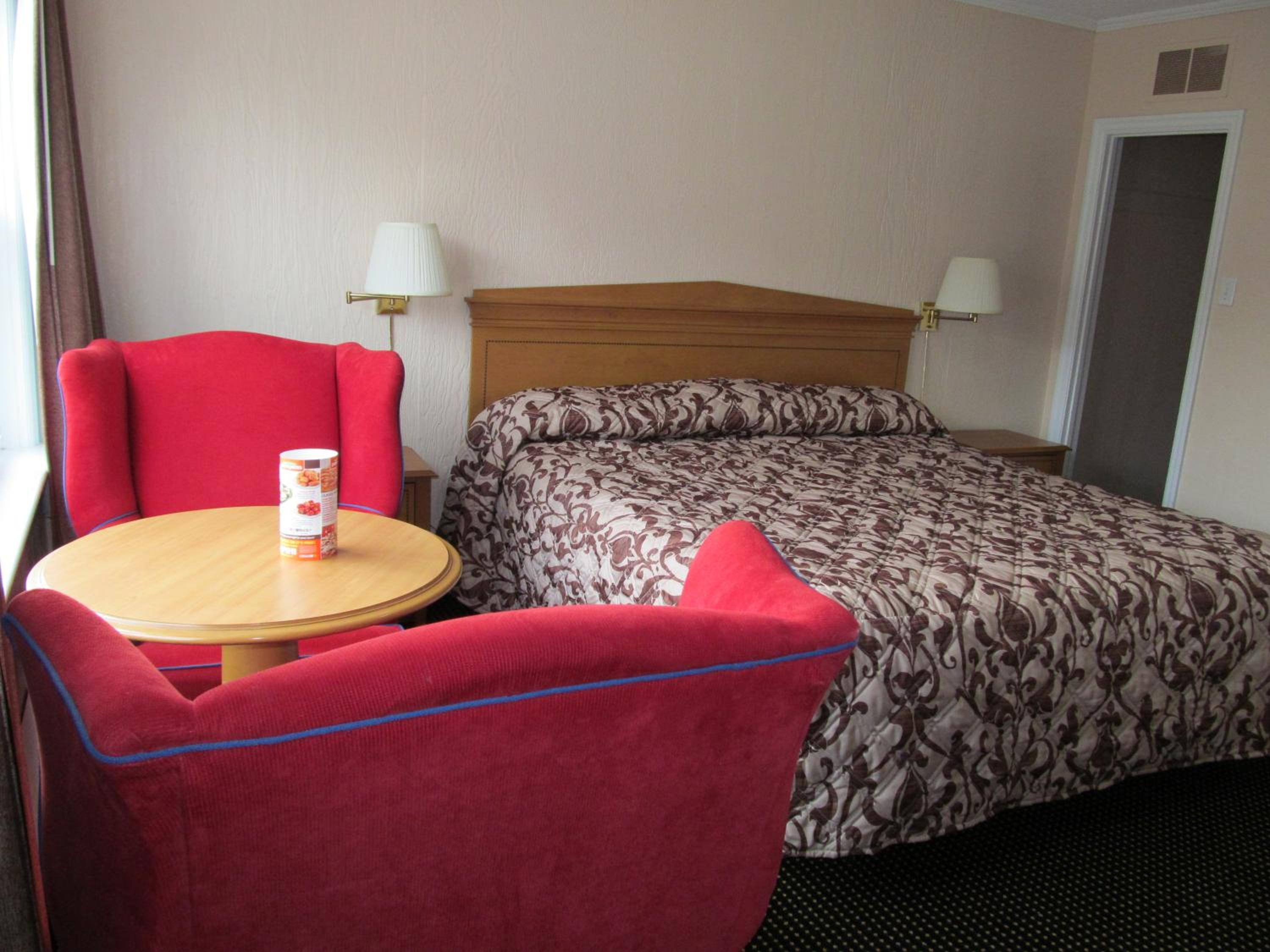 hotel room with a queen size bed and red chairs