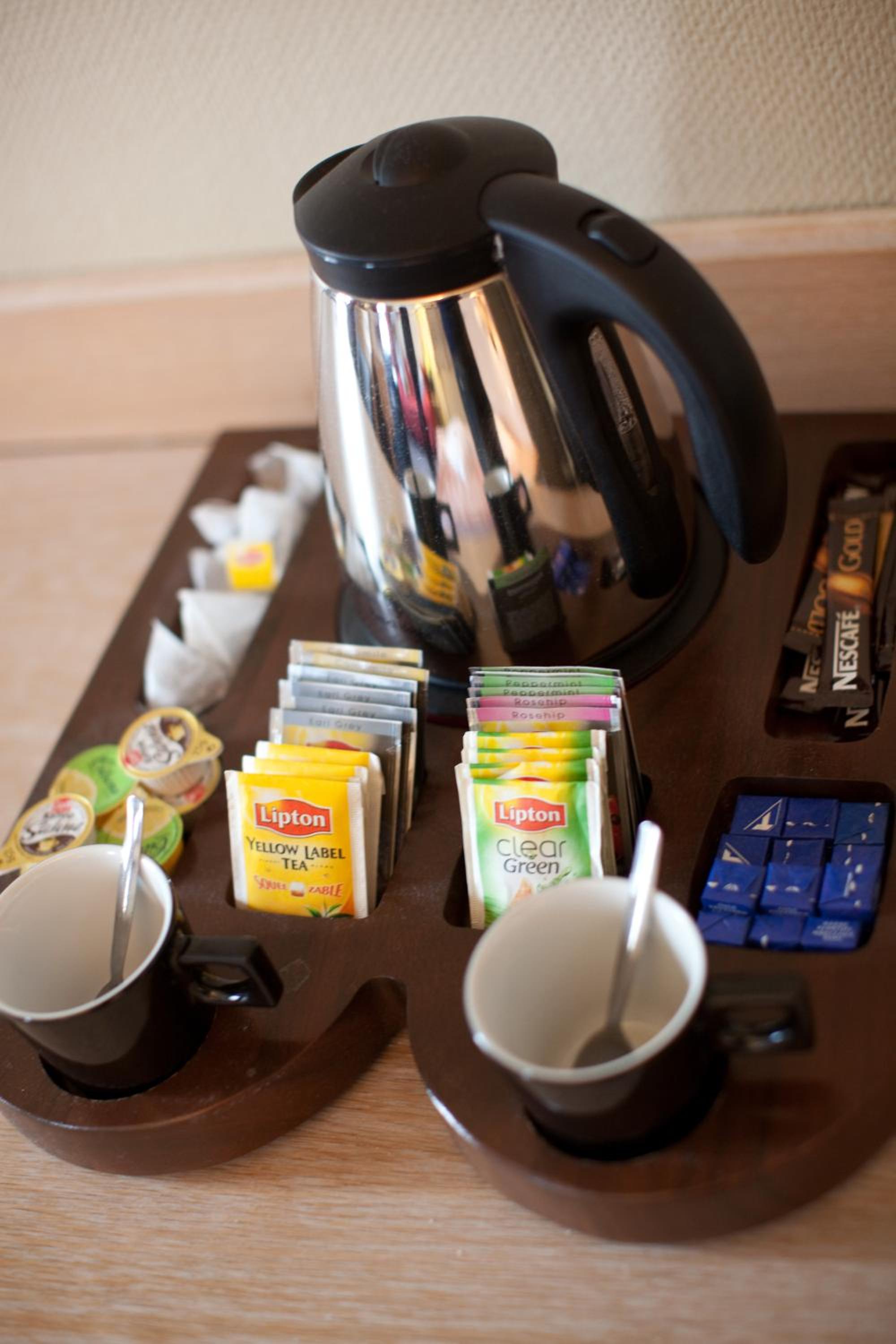 coffee maker, cups, and tea bags on a tray