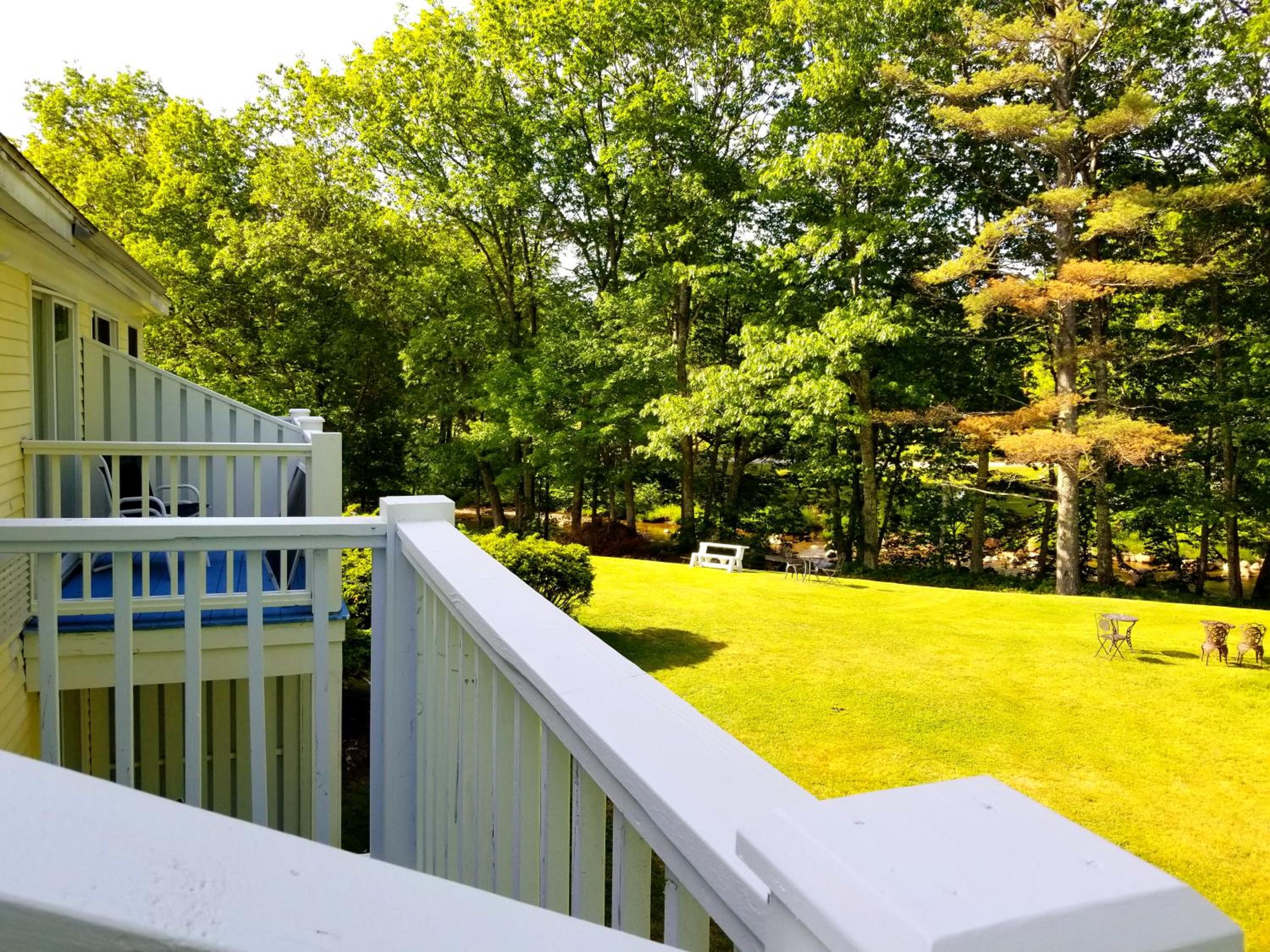 White balcony railing overlooking a green lawn and trees