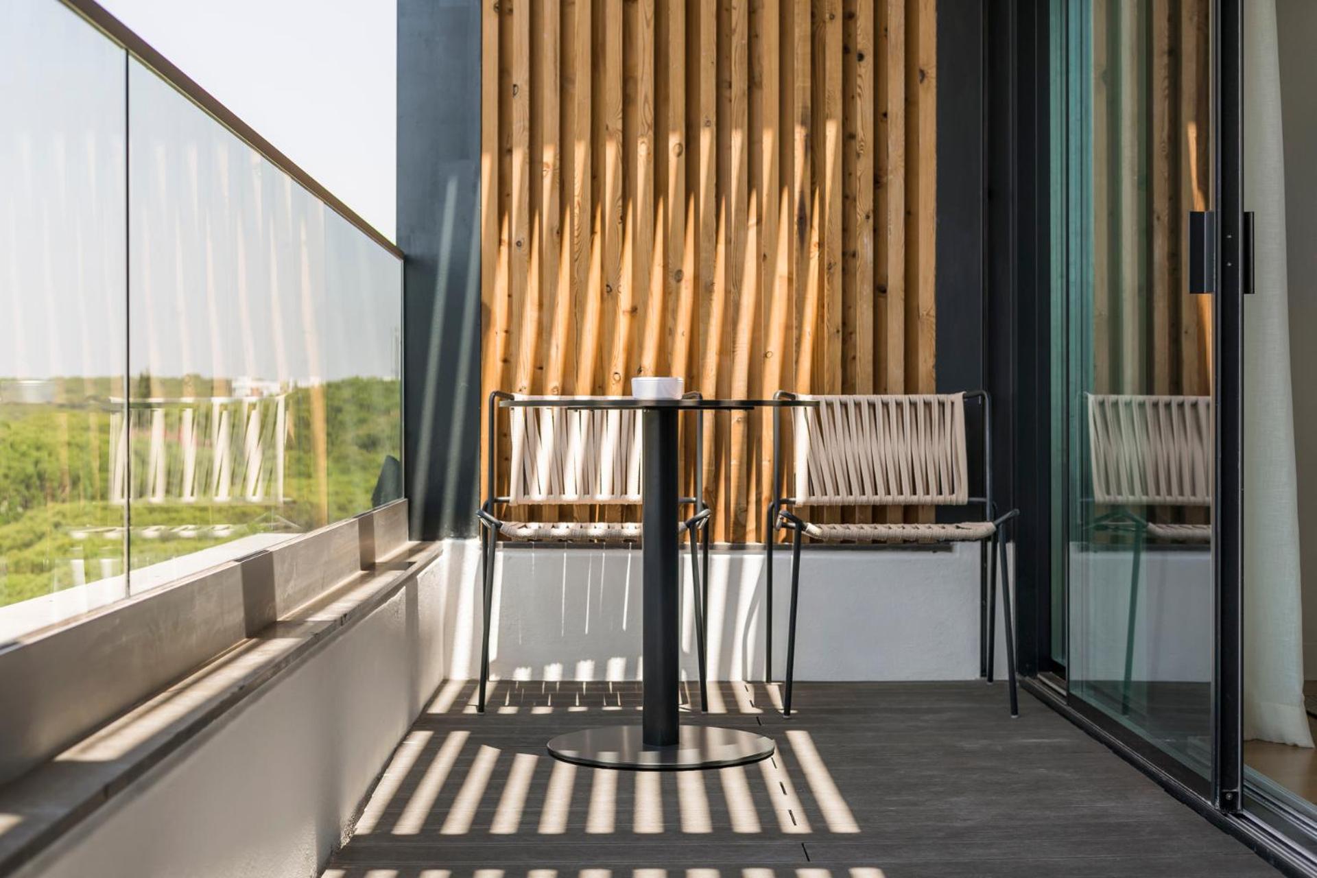 balcony with two chairs and a table in the sun