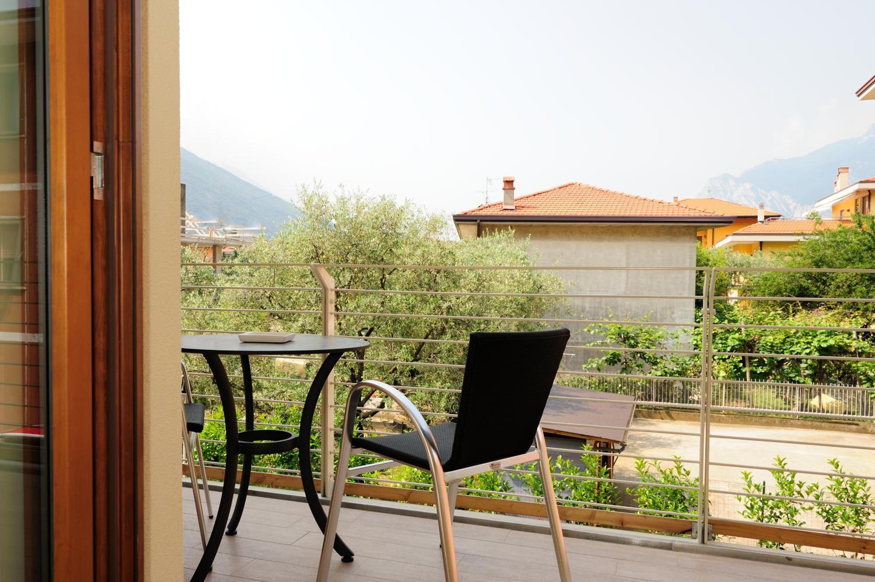 Balcony with bistro table and chairs overlooking olive trees and mountains