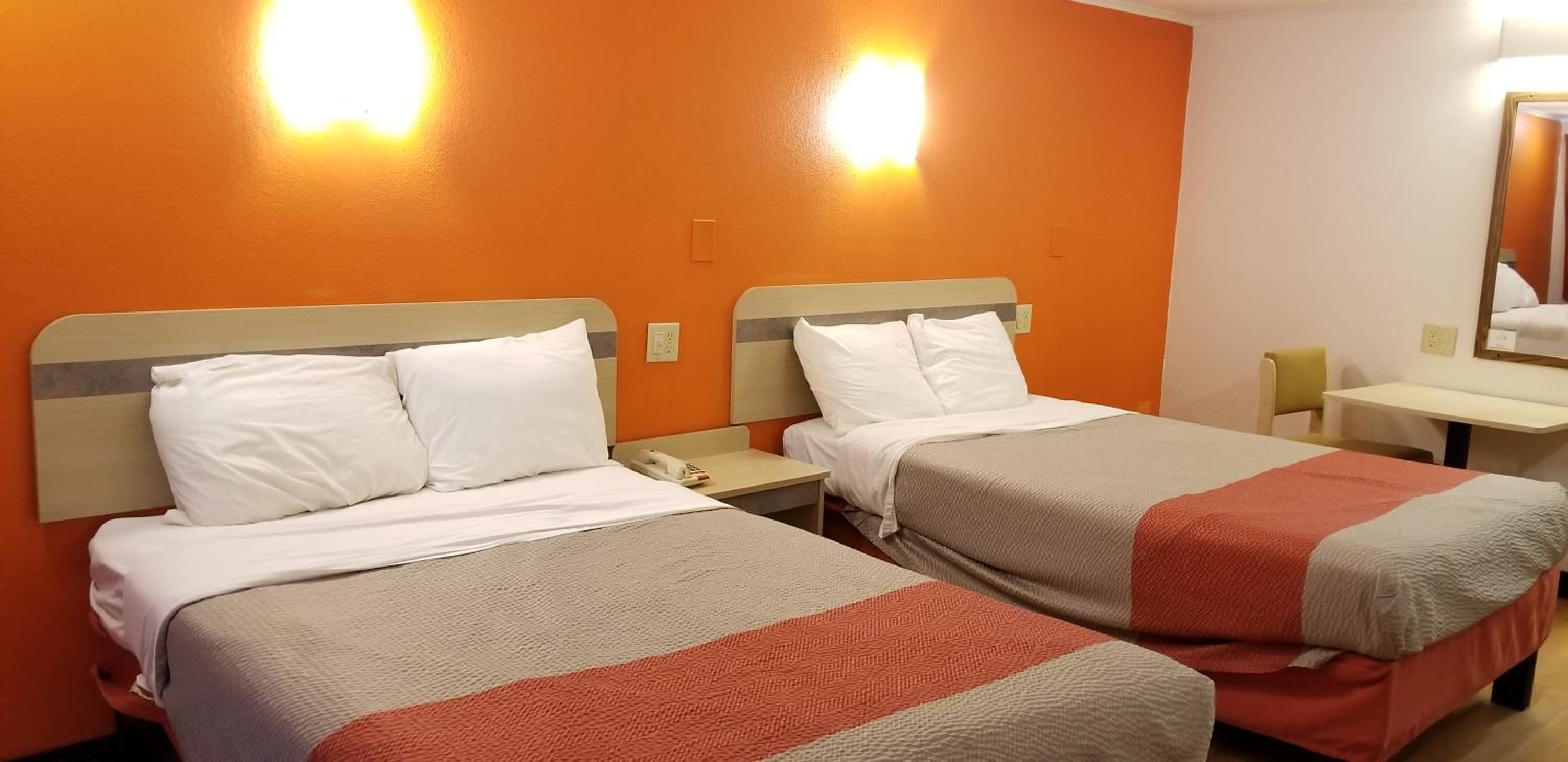 hotel room with two beds and an orange accent wall