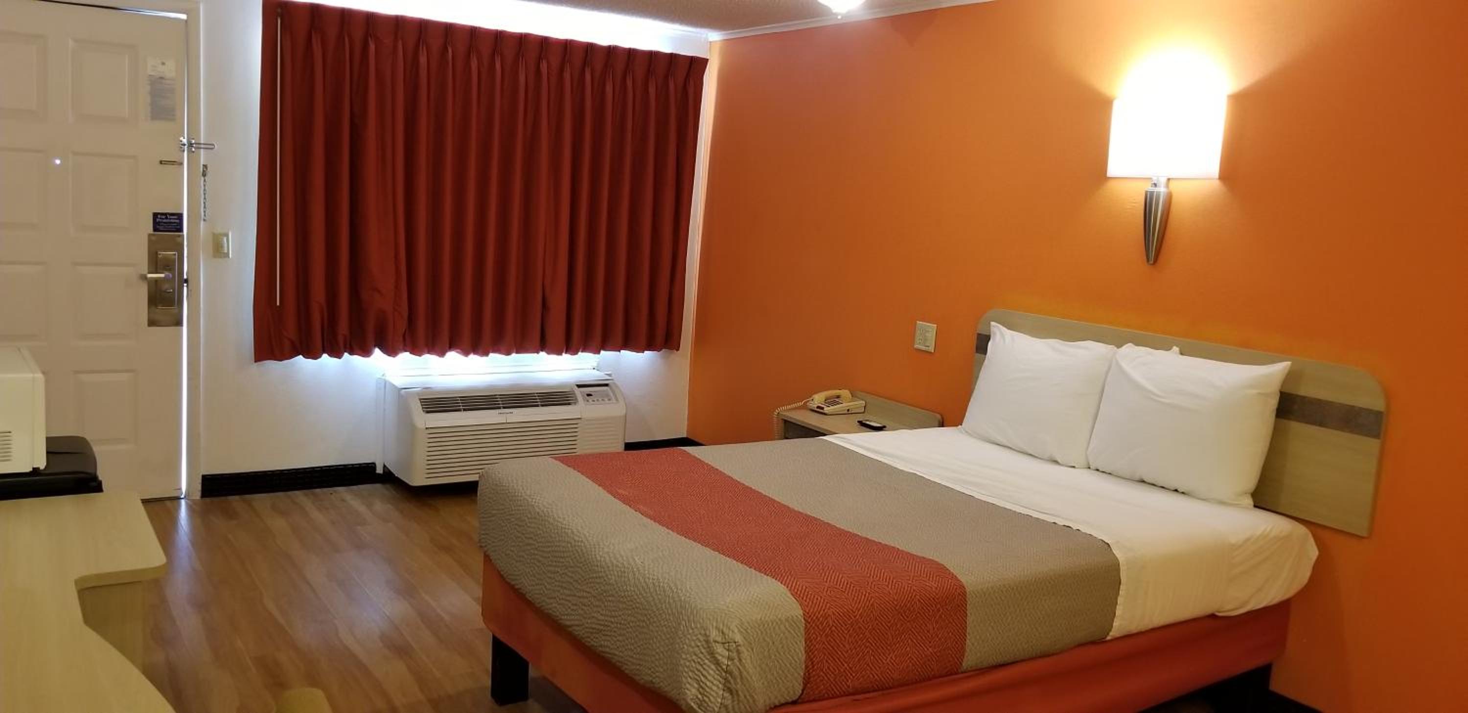 motel room with a bed, desk and air conditioner