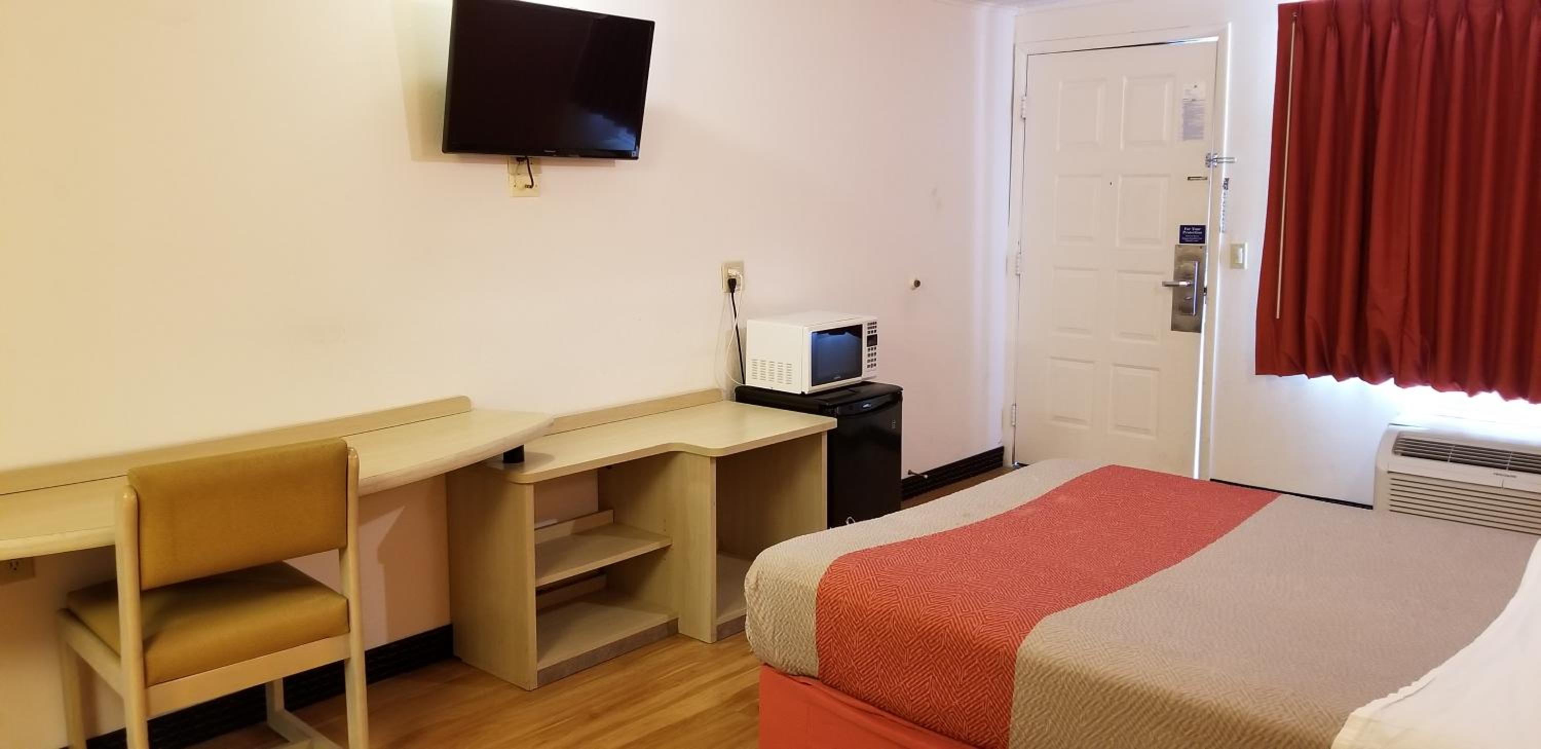 hotel room with a bed, desk, and television