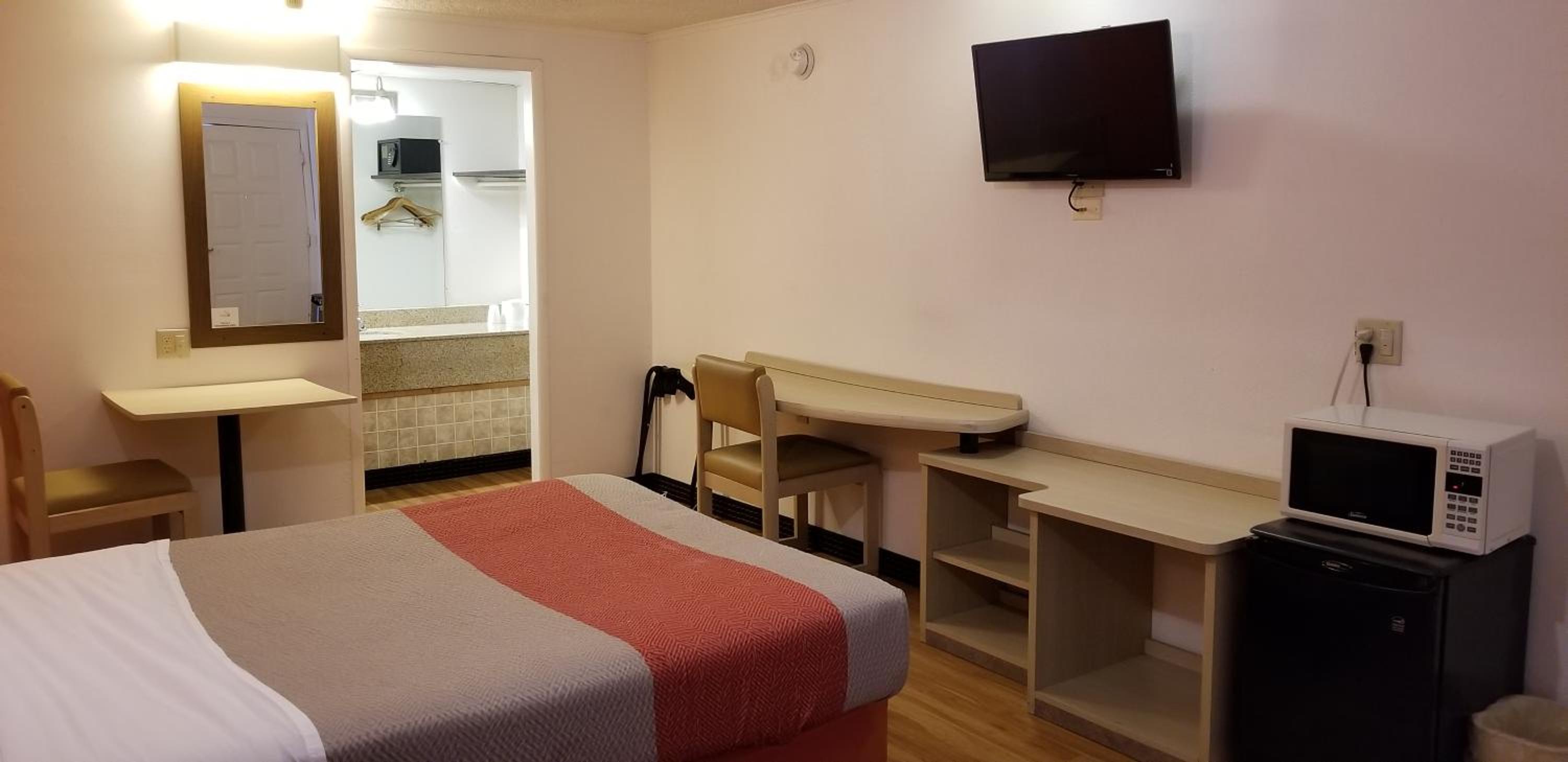 hotel room with a bed, desk, and television
