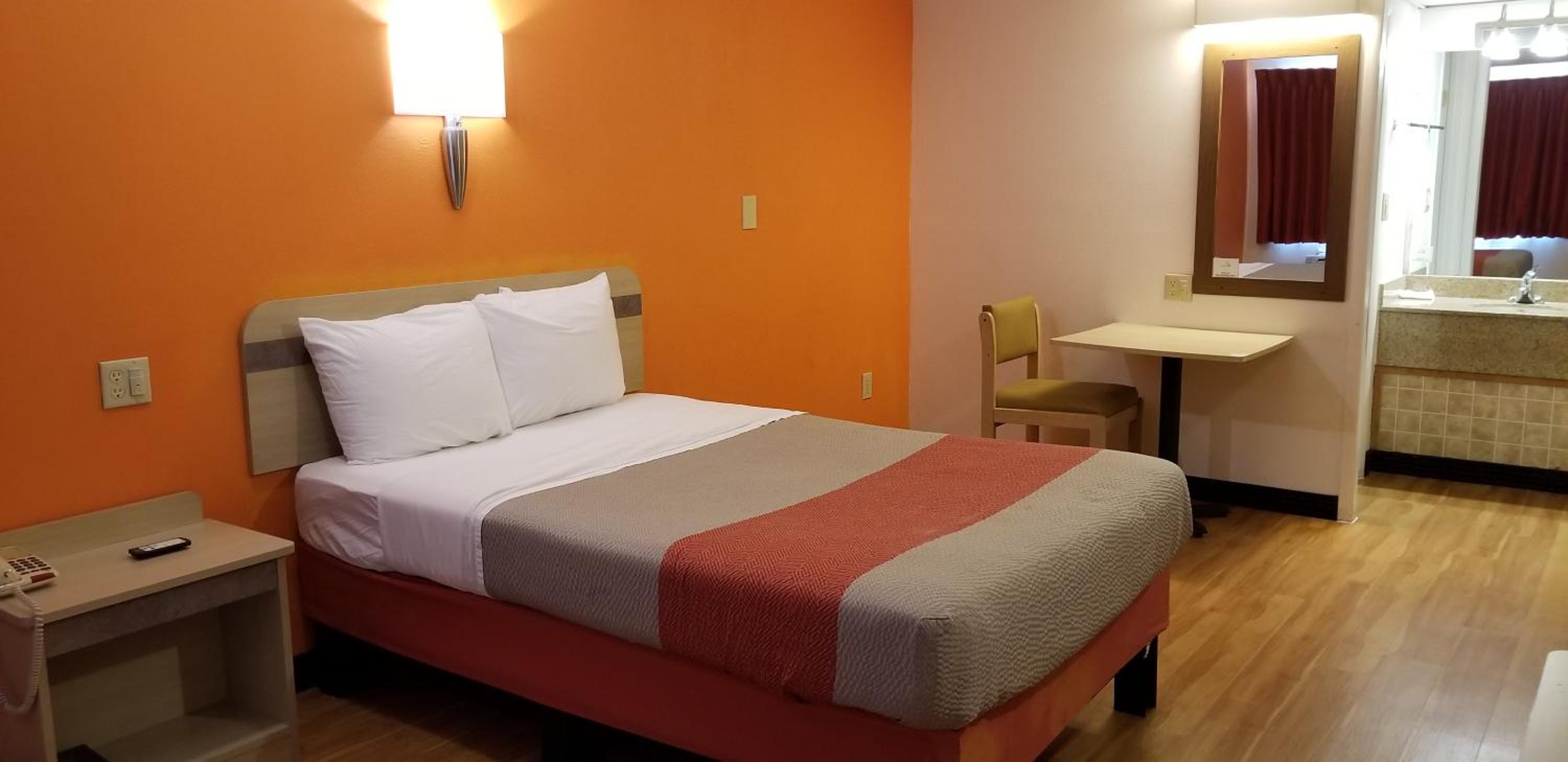 hotel room with a bed, desk, and mirror