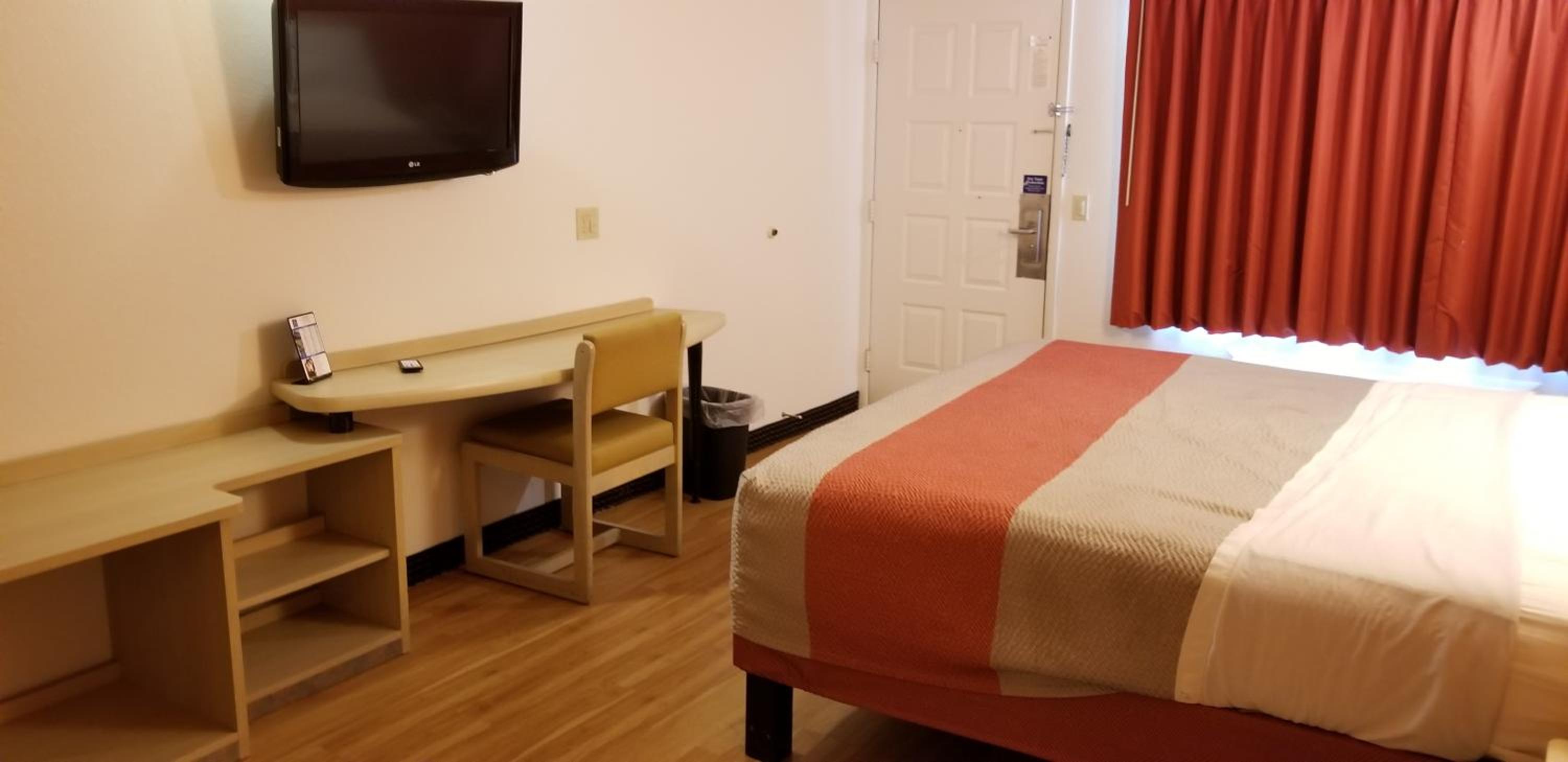 hotel room with a bed, desk, and television