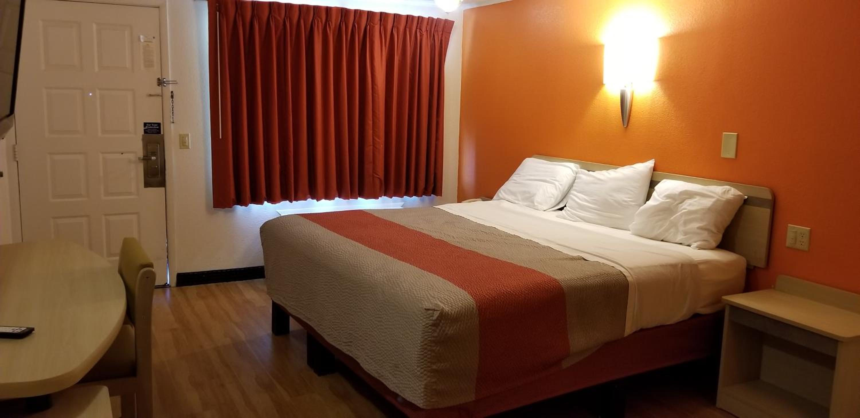 motel room with a bed, desk, and tv