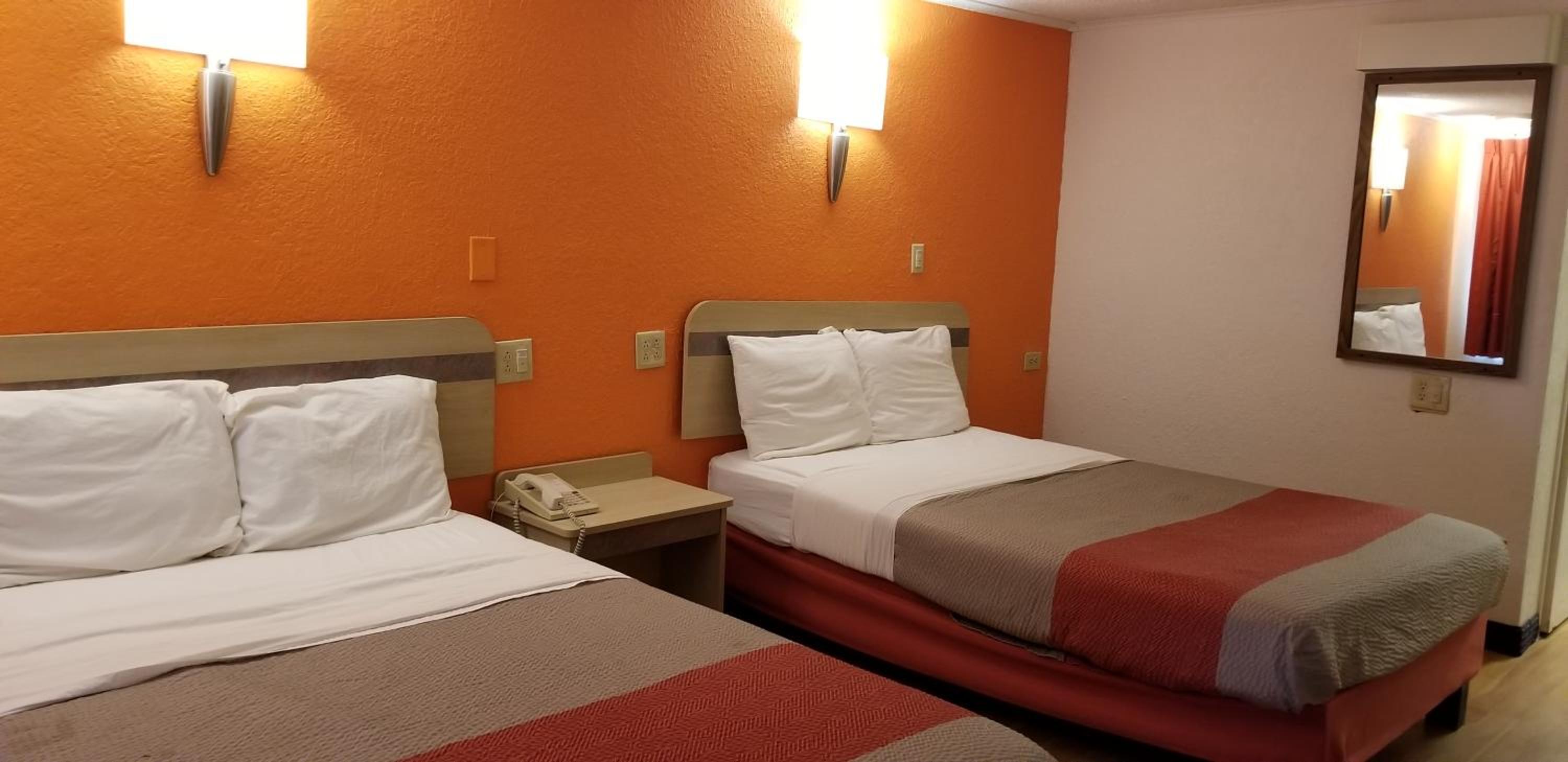 hotel room with two beds and an orange accent wall