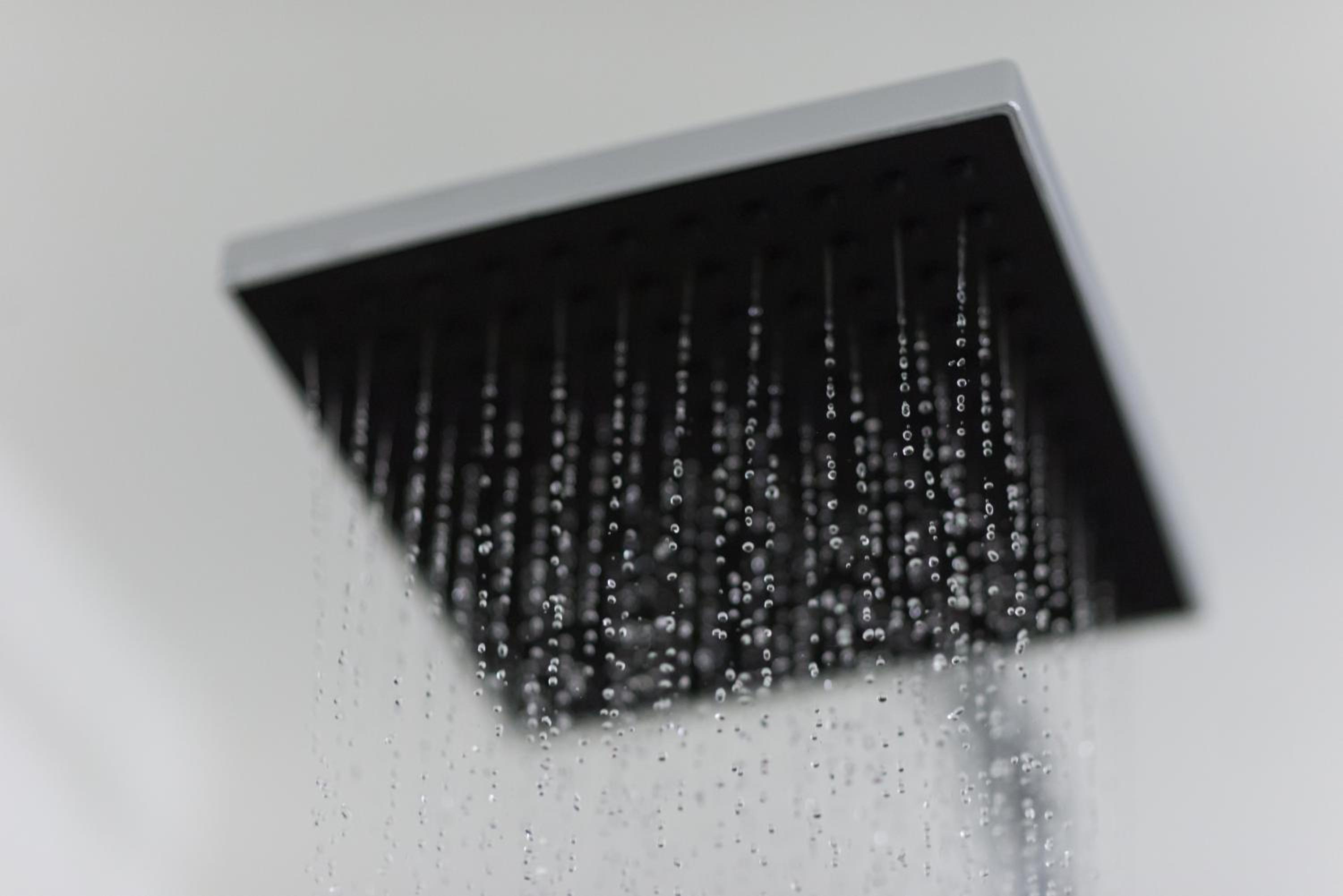 close up of a shower head with water running down it