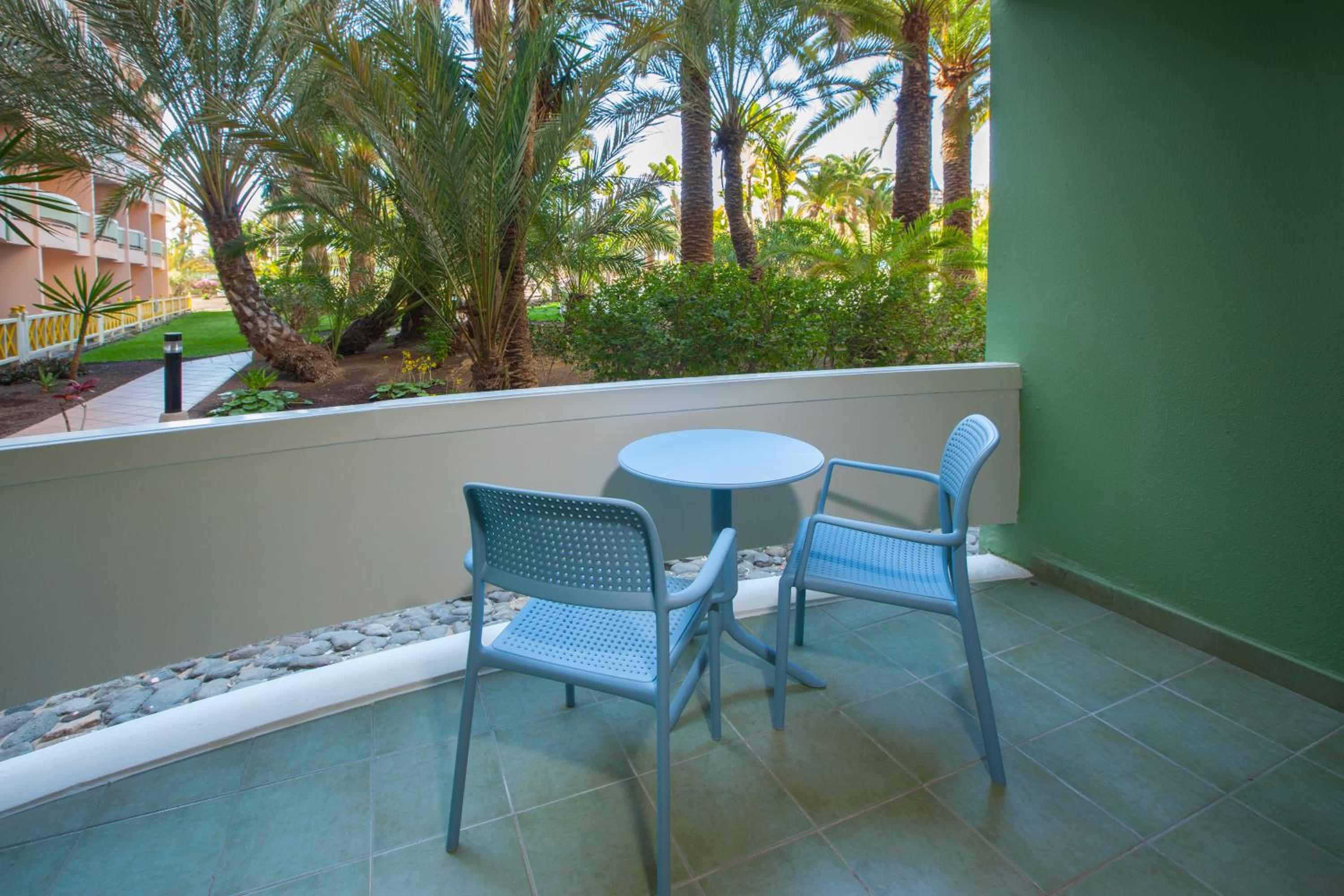 balcony with two blue chairs and a table on it