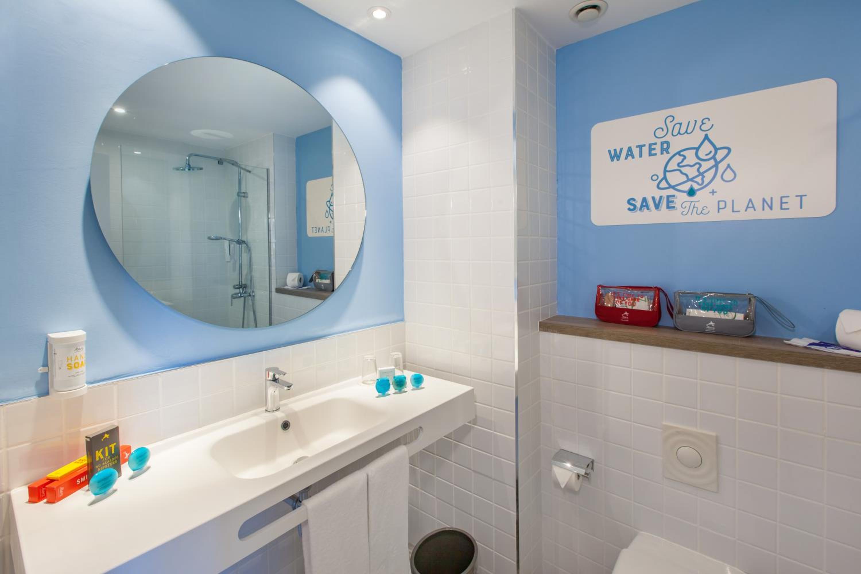 blue and white bathroom with a round mirror above the sink