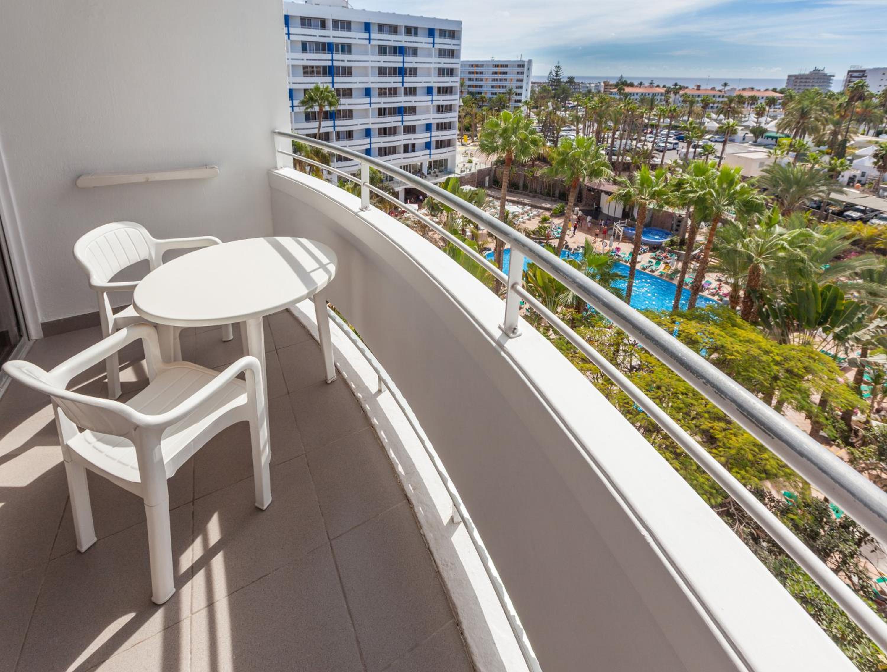 balcony with a table and two chairs overlooking the pool
