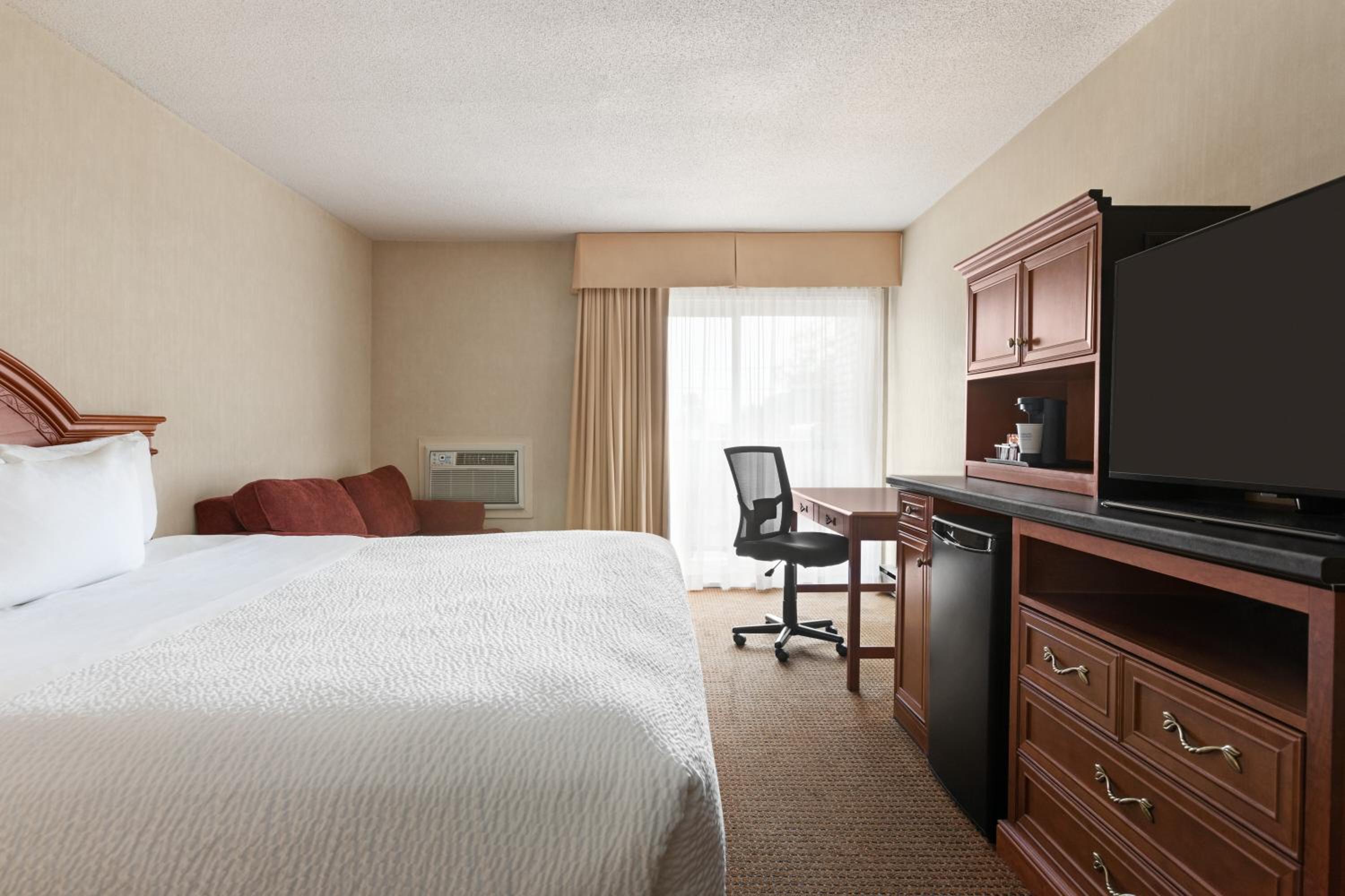 hotel room with a bed, desk, and television