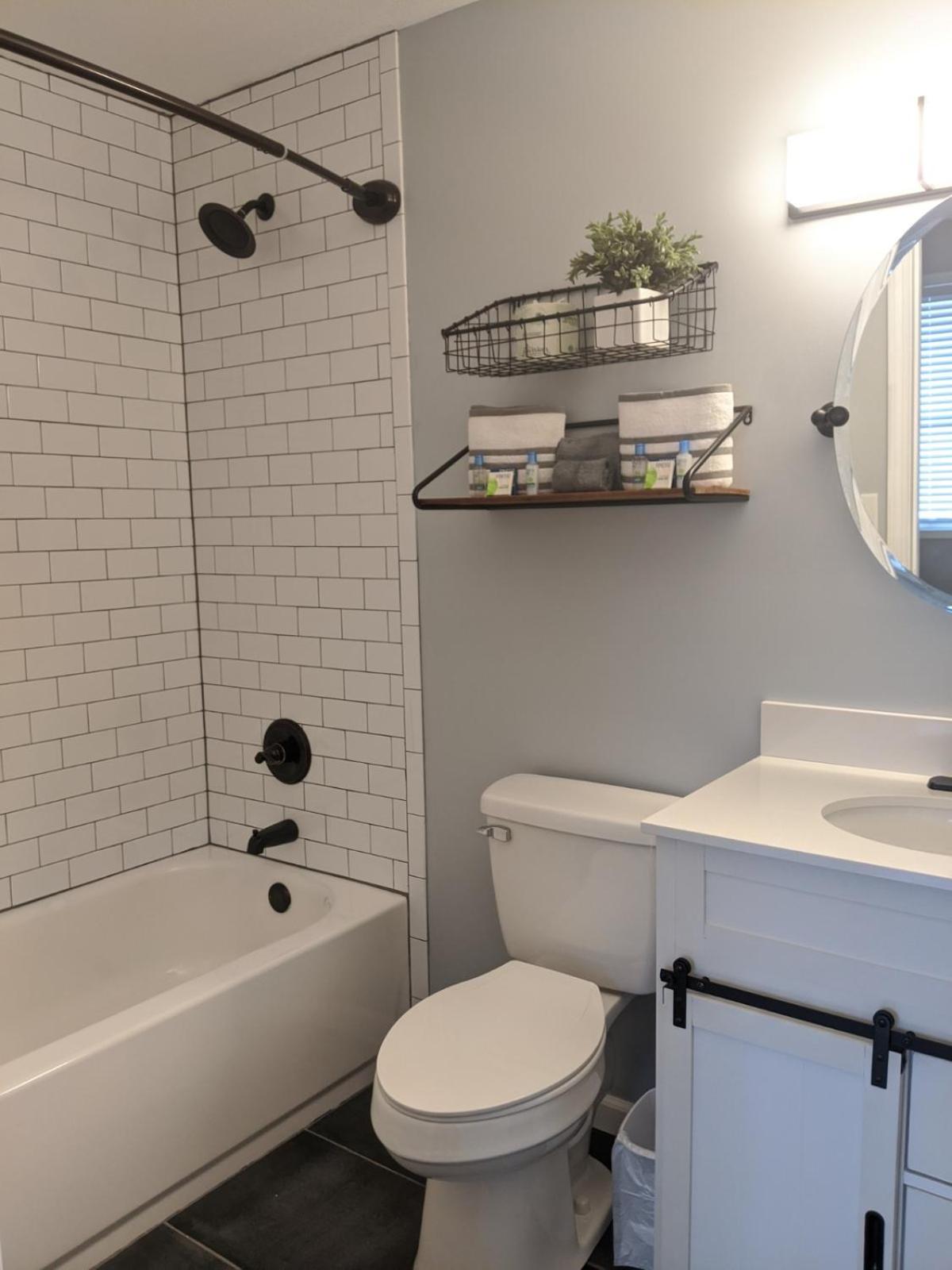 White tiled bathroom with tub, toilet, and vanity