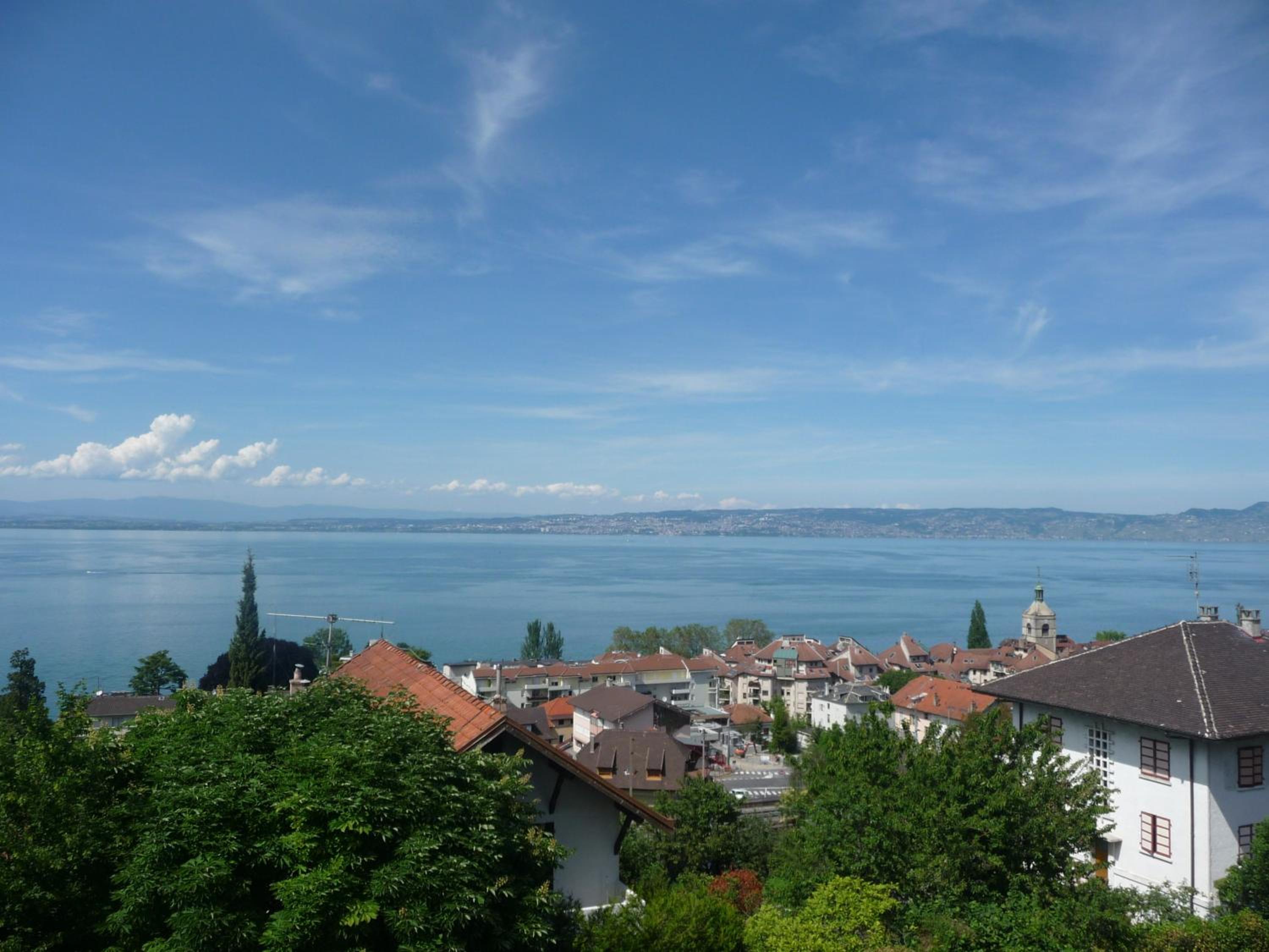 Elevated view over rooftops and town to a large lake and distant shore