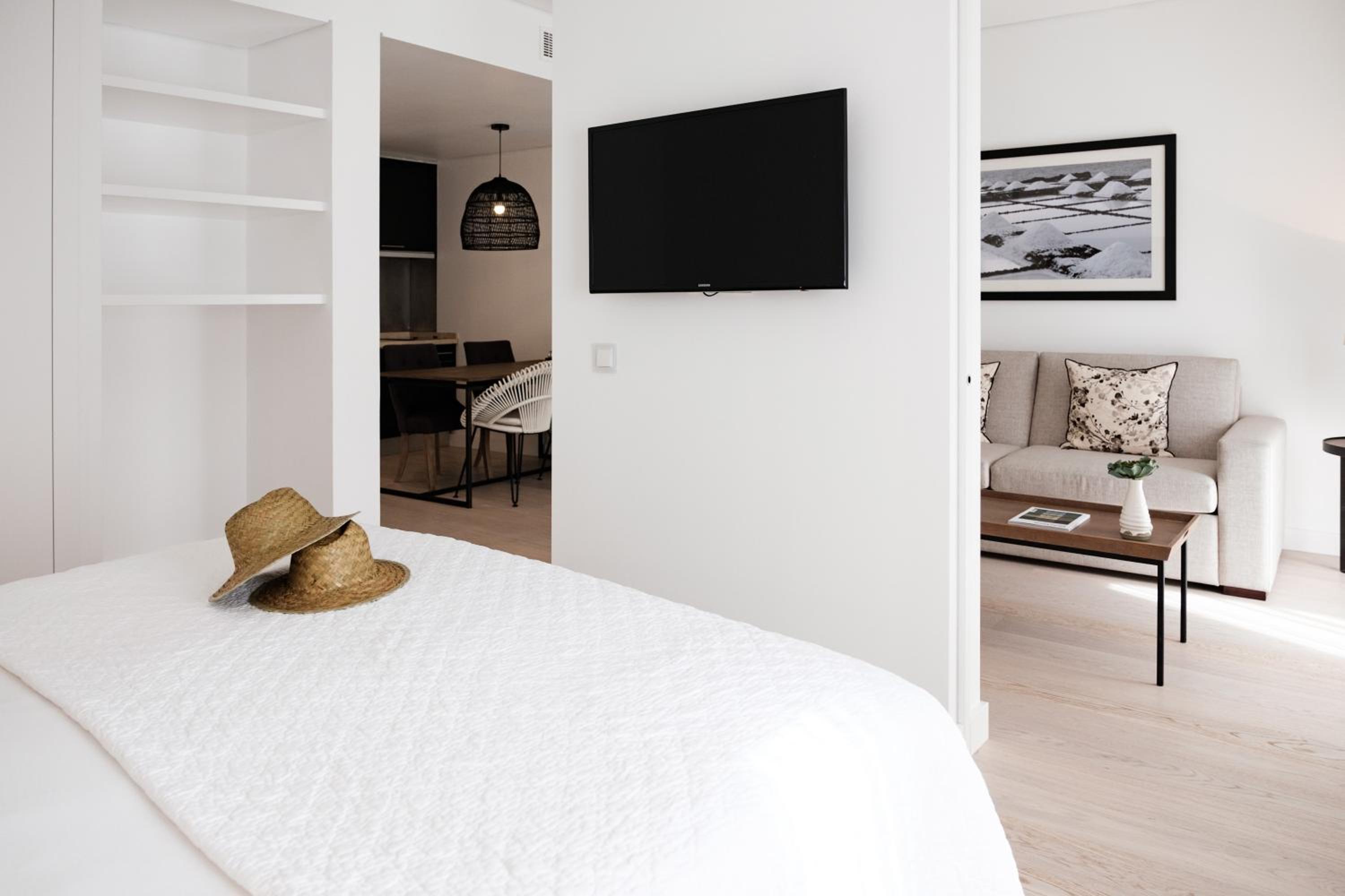 white bedroom with a flat screen tv on the wall