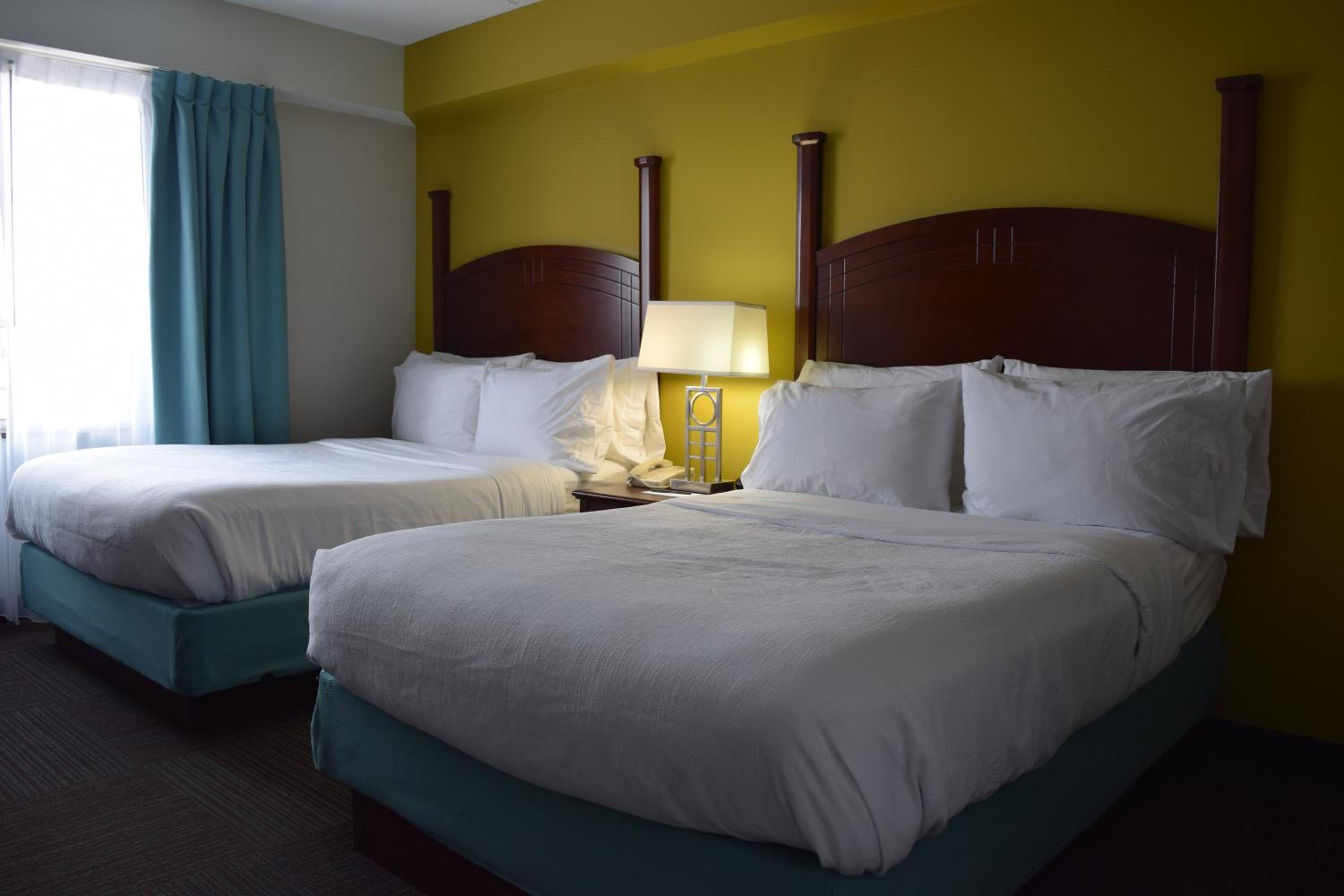 hotel room with two queen sized beds and a bright yellow wall