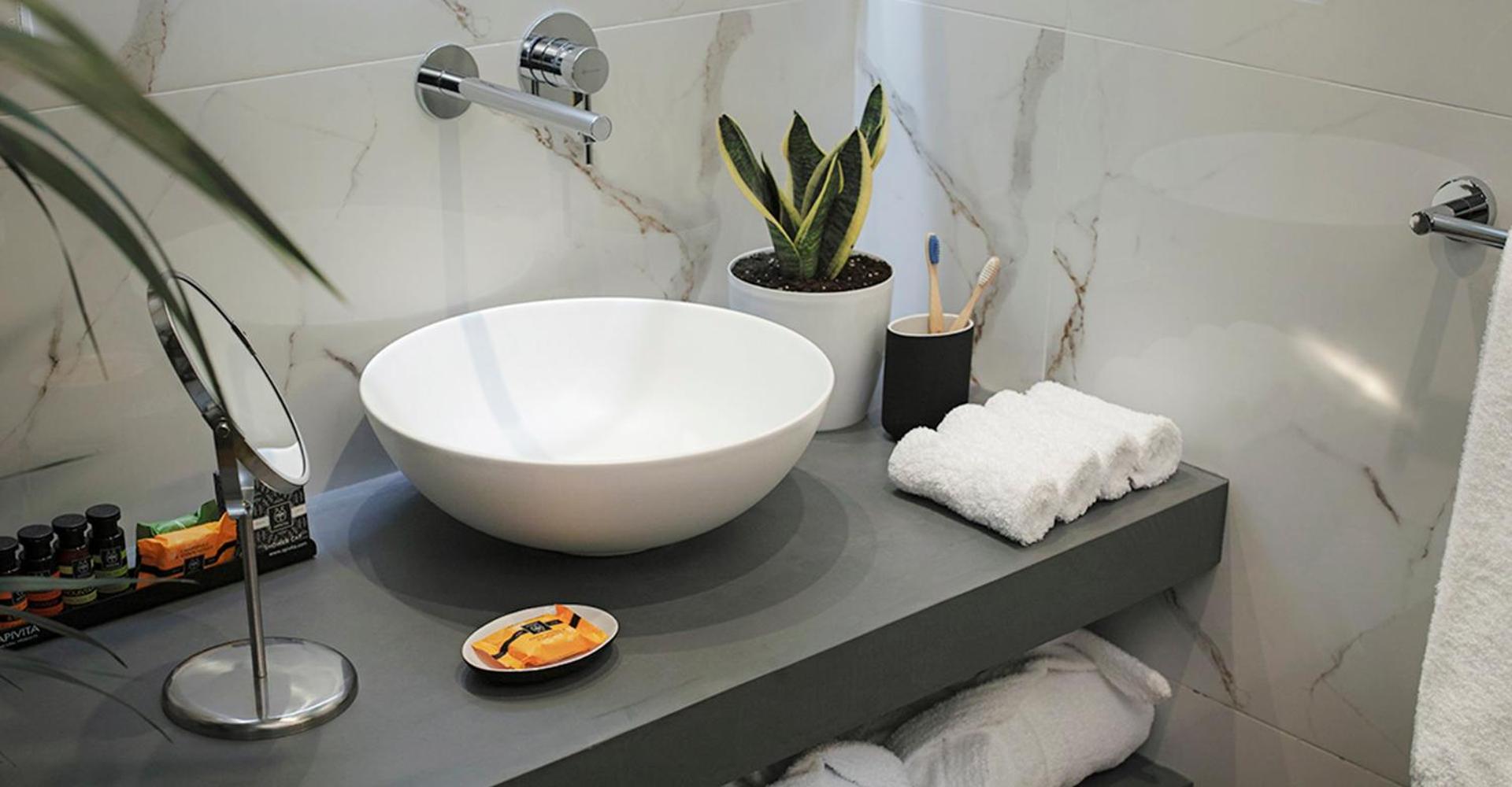 Bathroom vanity with a white vessel sink, marble walls, and folded white towels.