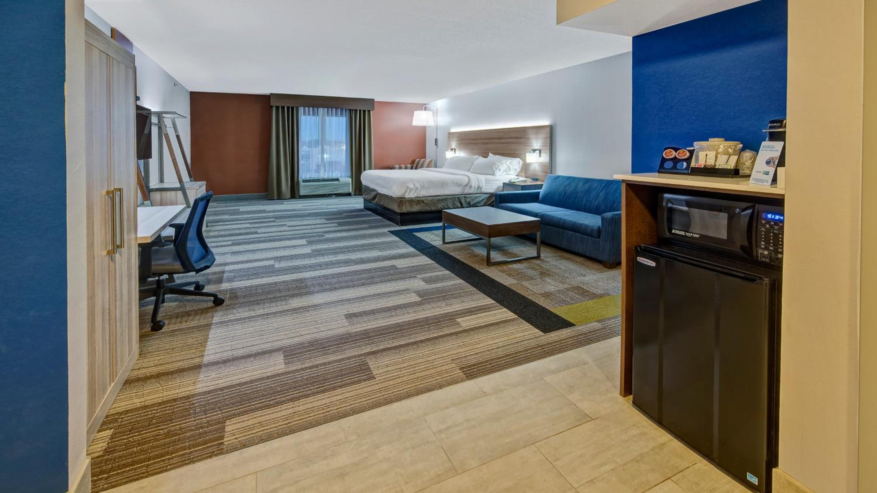 hotel room with a couch, desk, and microwave
