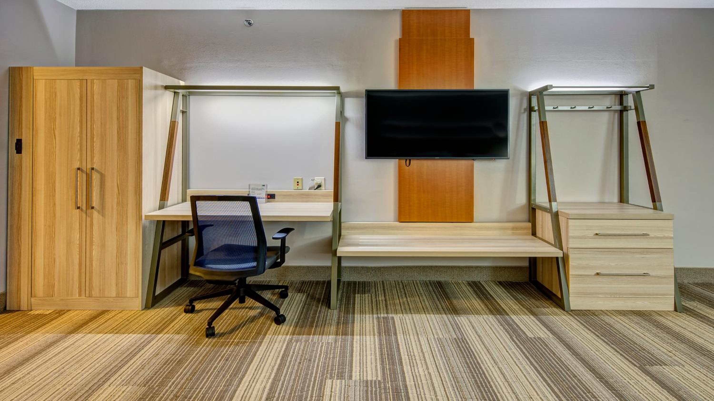 room with a bed, desk, chair and television