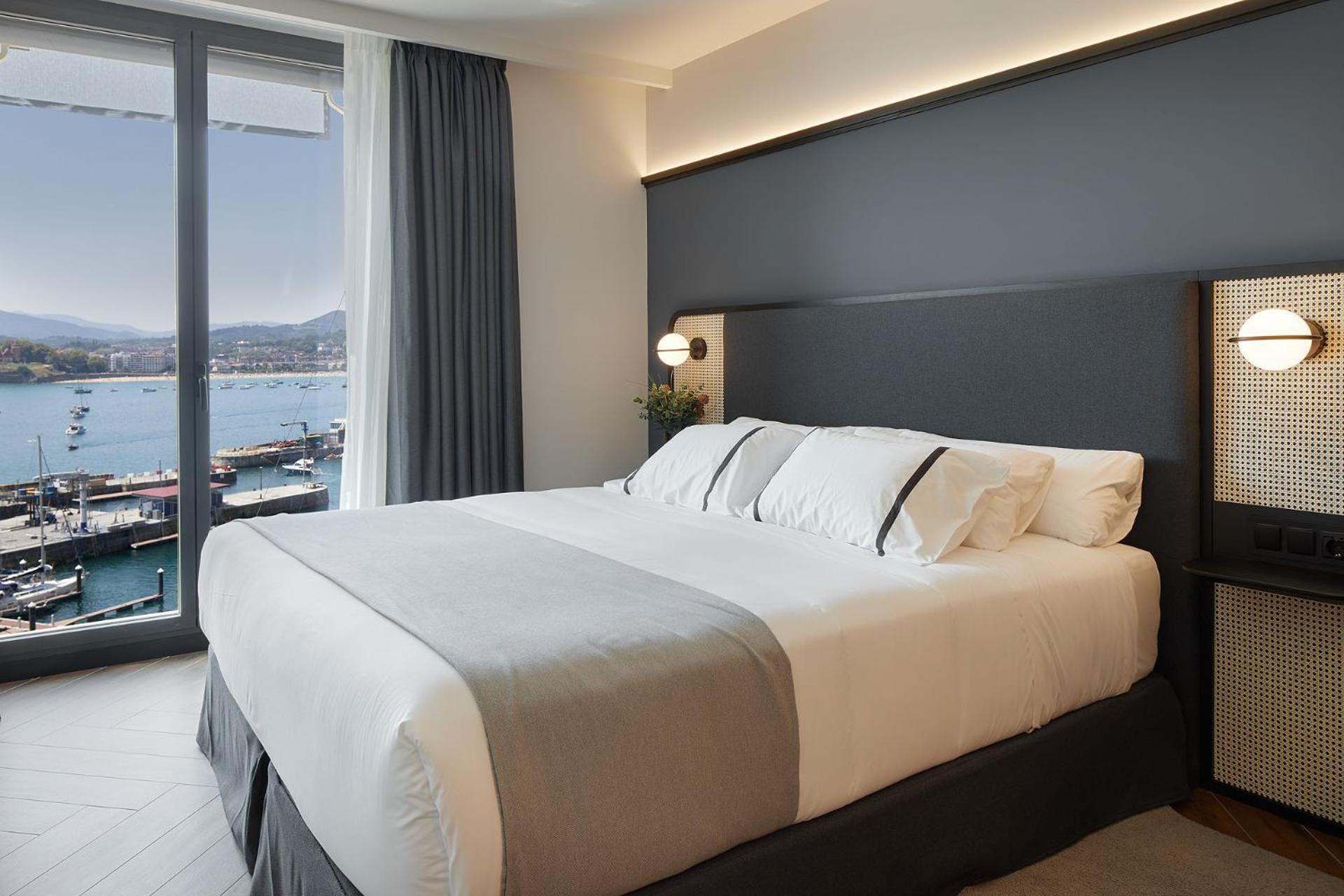 Modern bedroom with double bed and harbor view through floor-to-ceiling window