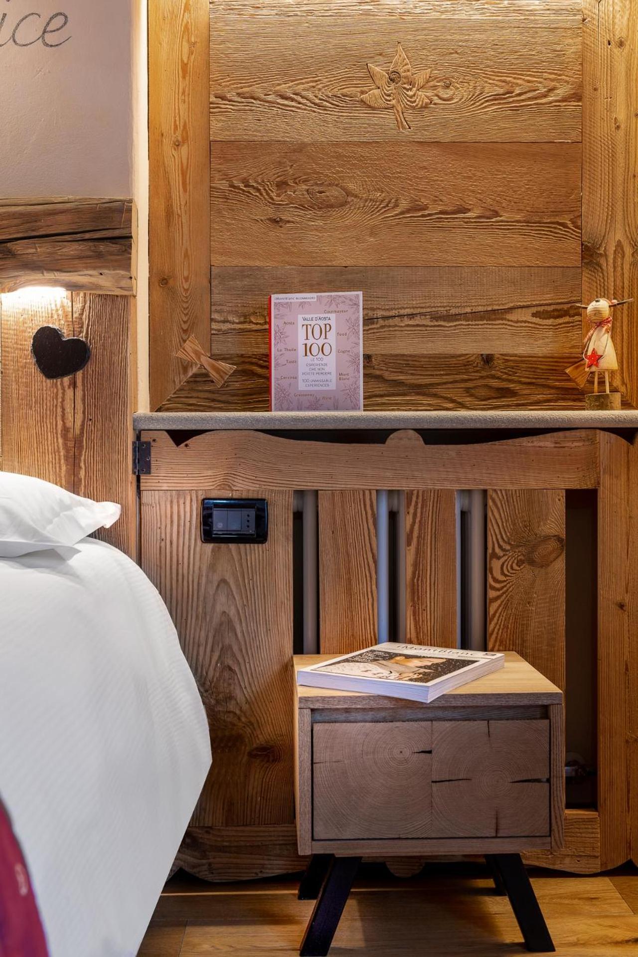 Rustic wood bedside nightstand with guidebook beside a white-linen bed