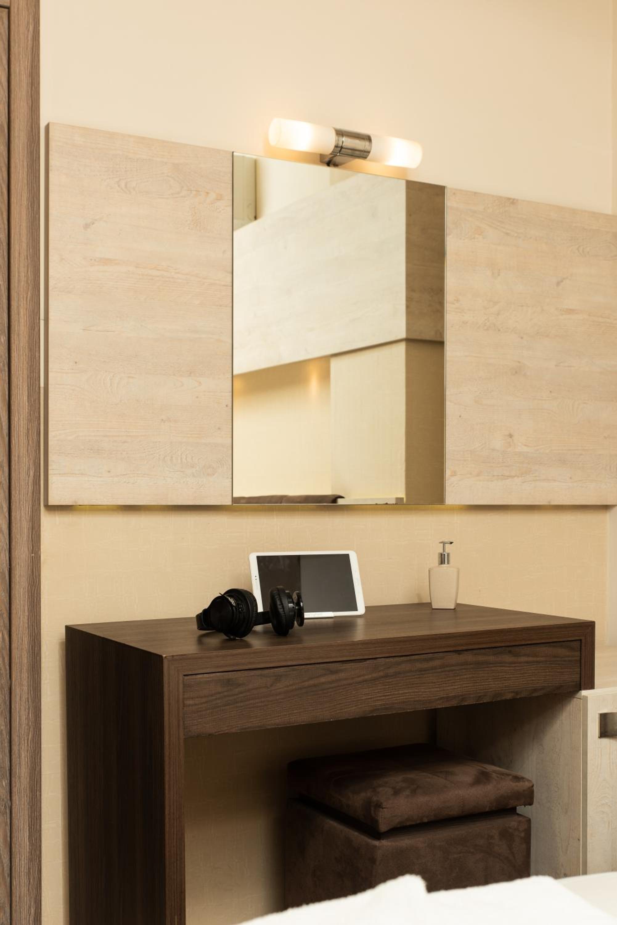 Hotel room desk with a mirror, headphones, and a tablet.
