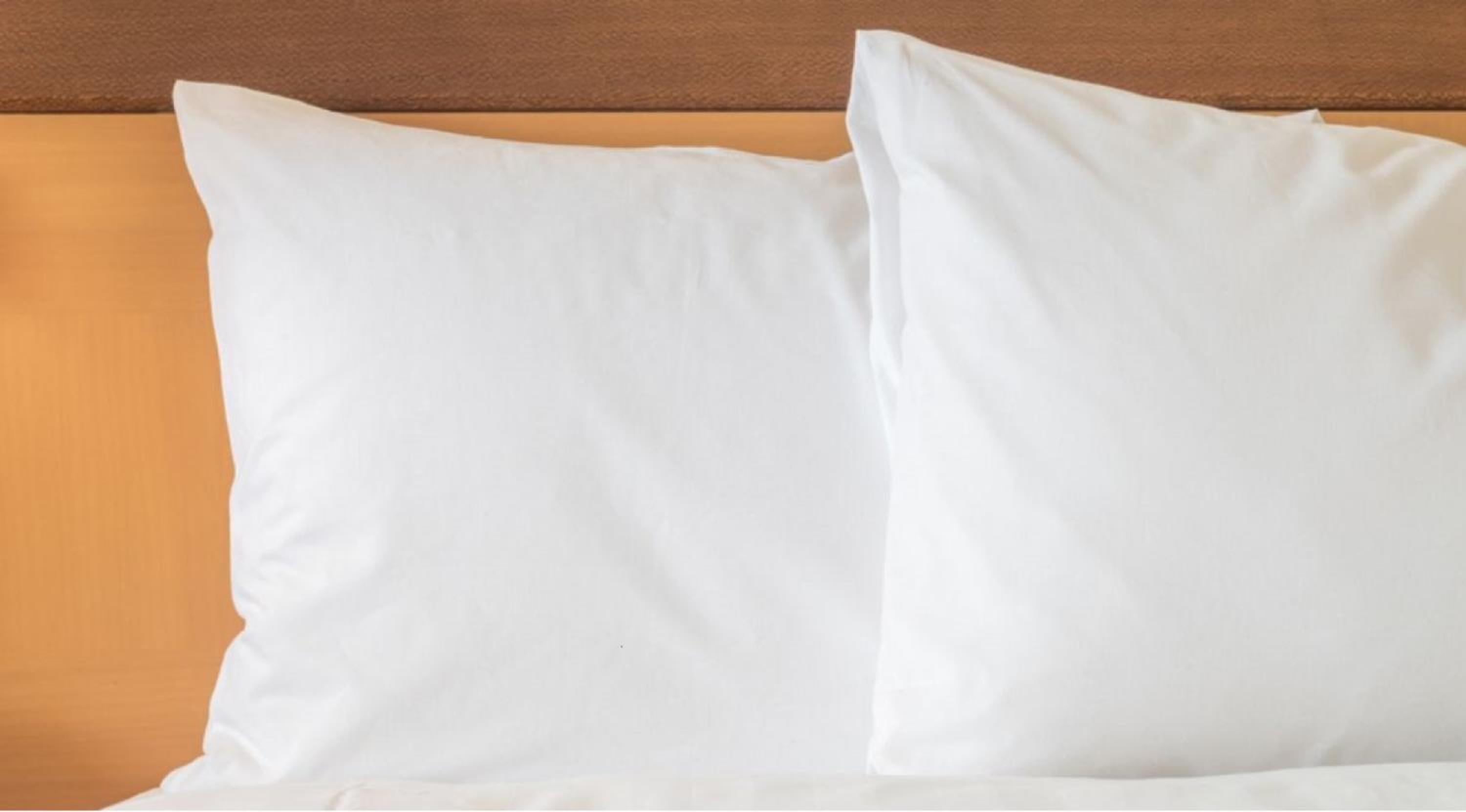 closeup of two white pillows on a hotel bed