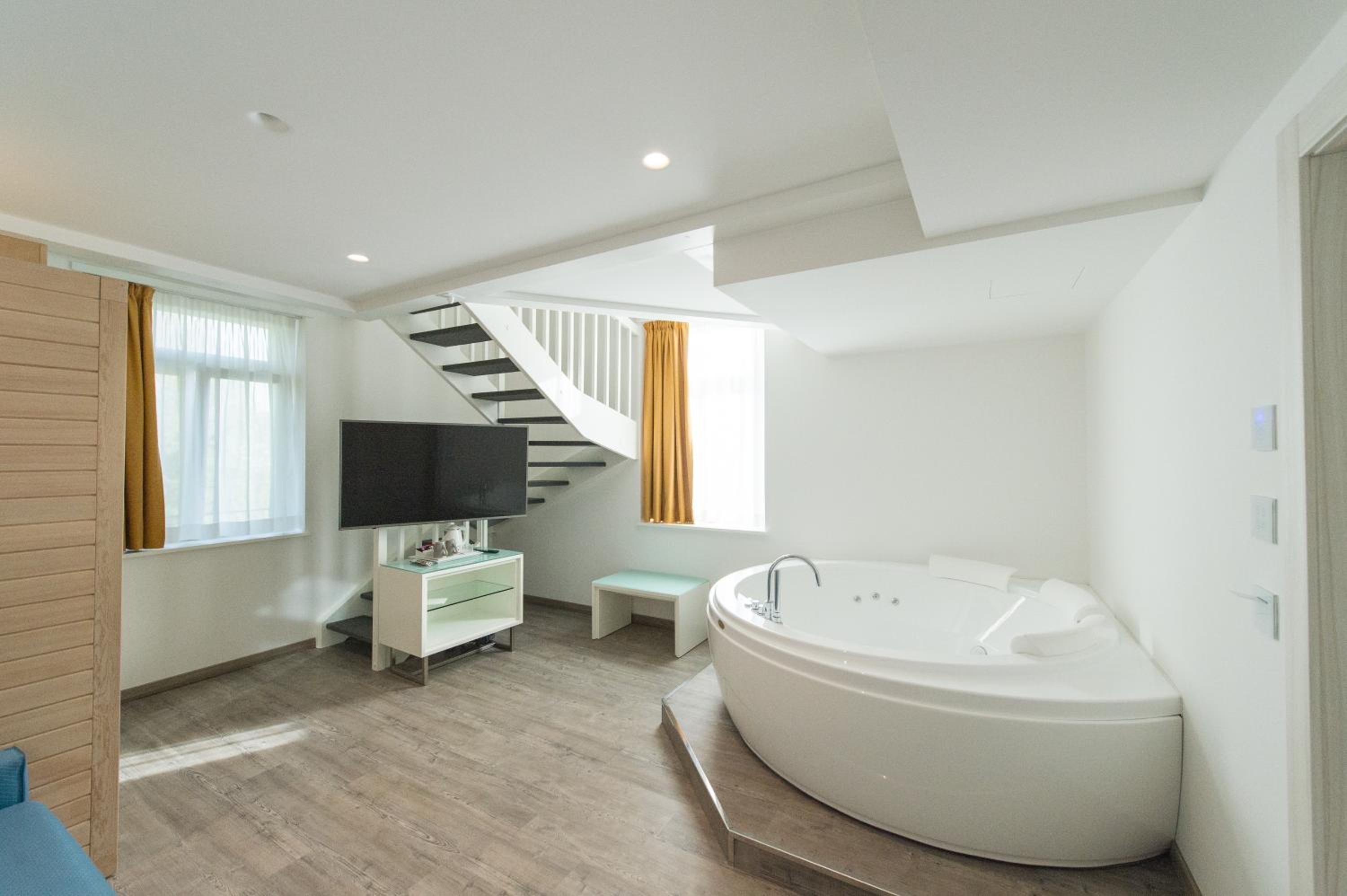 Hotel room with a large white freestanding bathtub and a staircase.