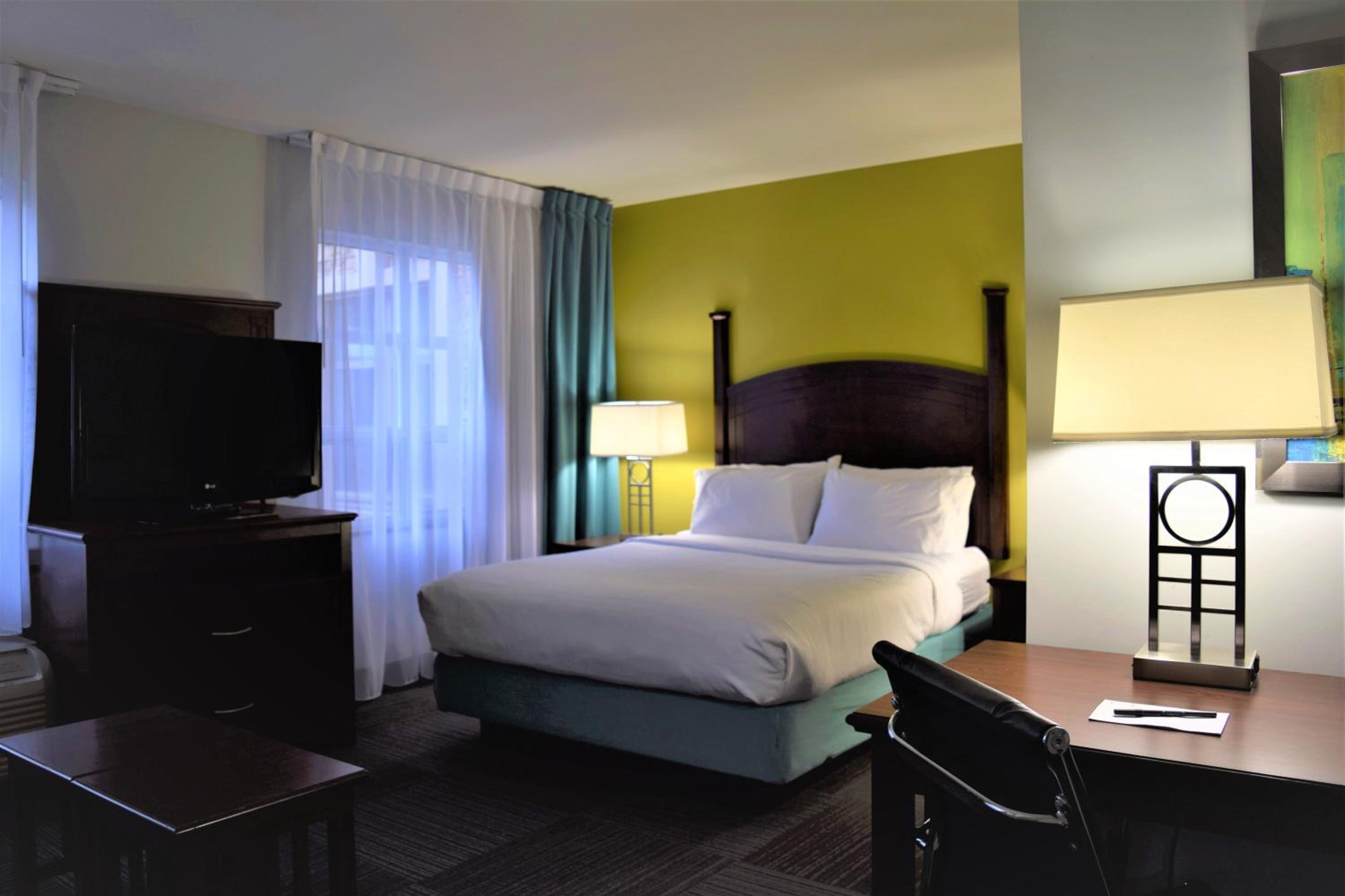 hotel room with a bed, desk, and television