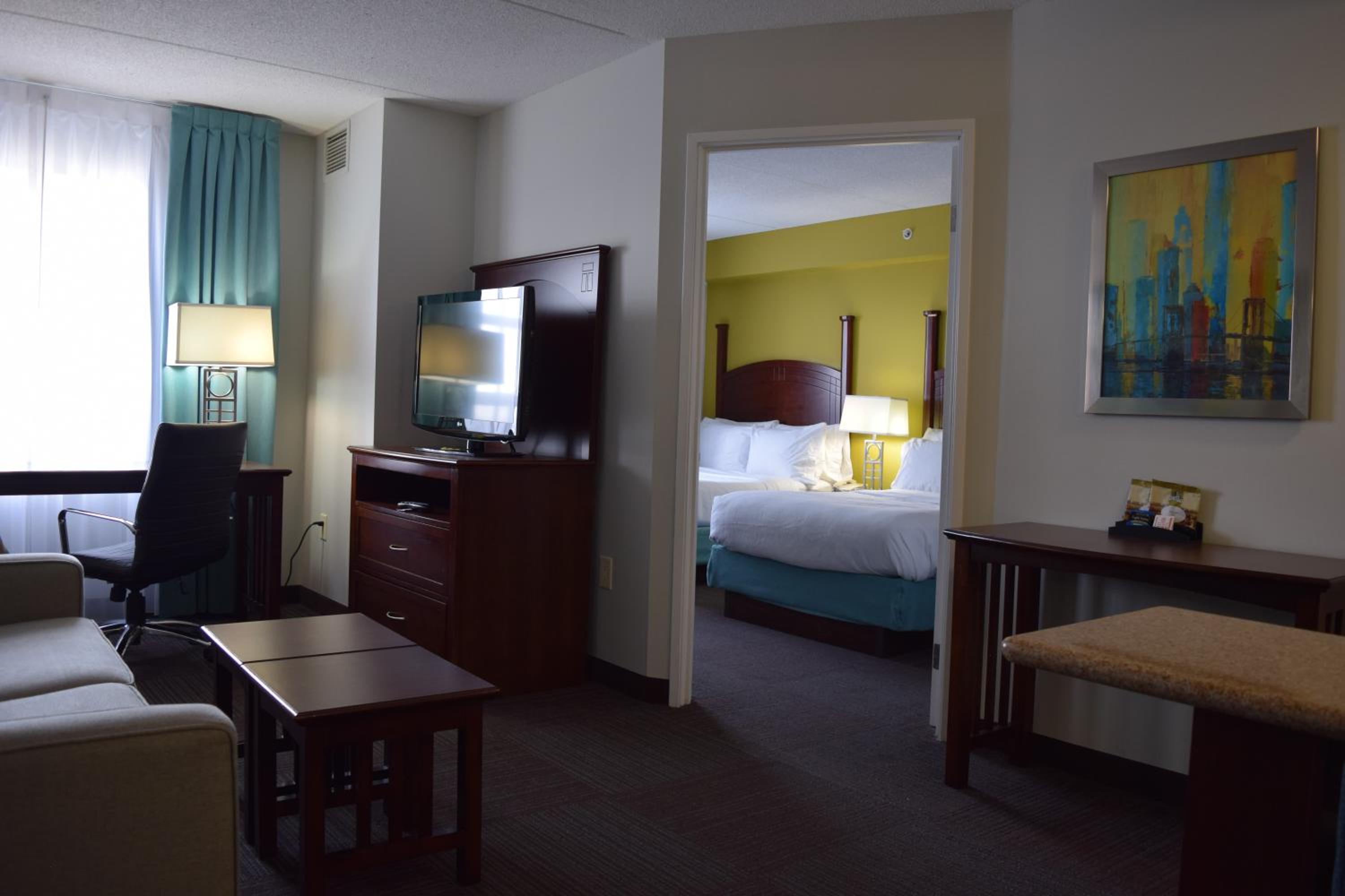 hotel room with a couch, coffee table and television