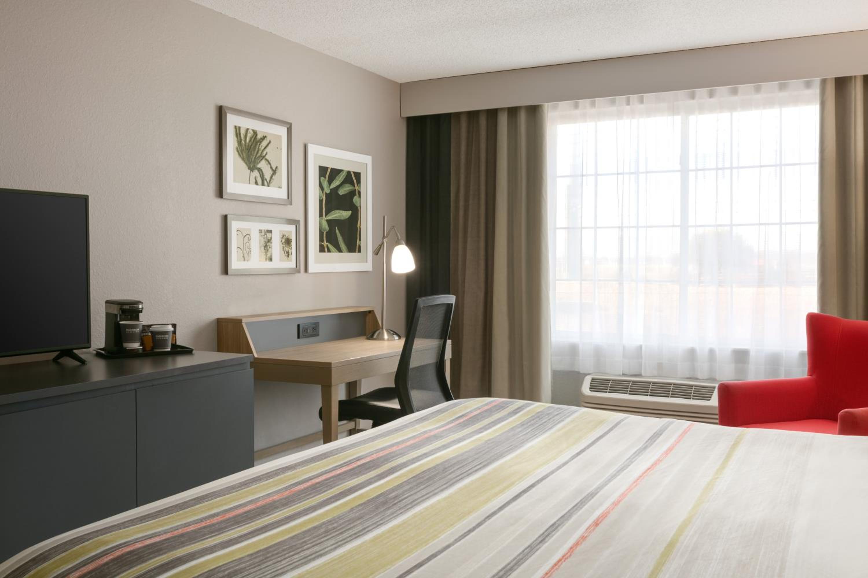 hotel room with a bed, desk, and television