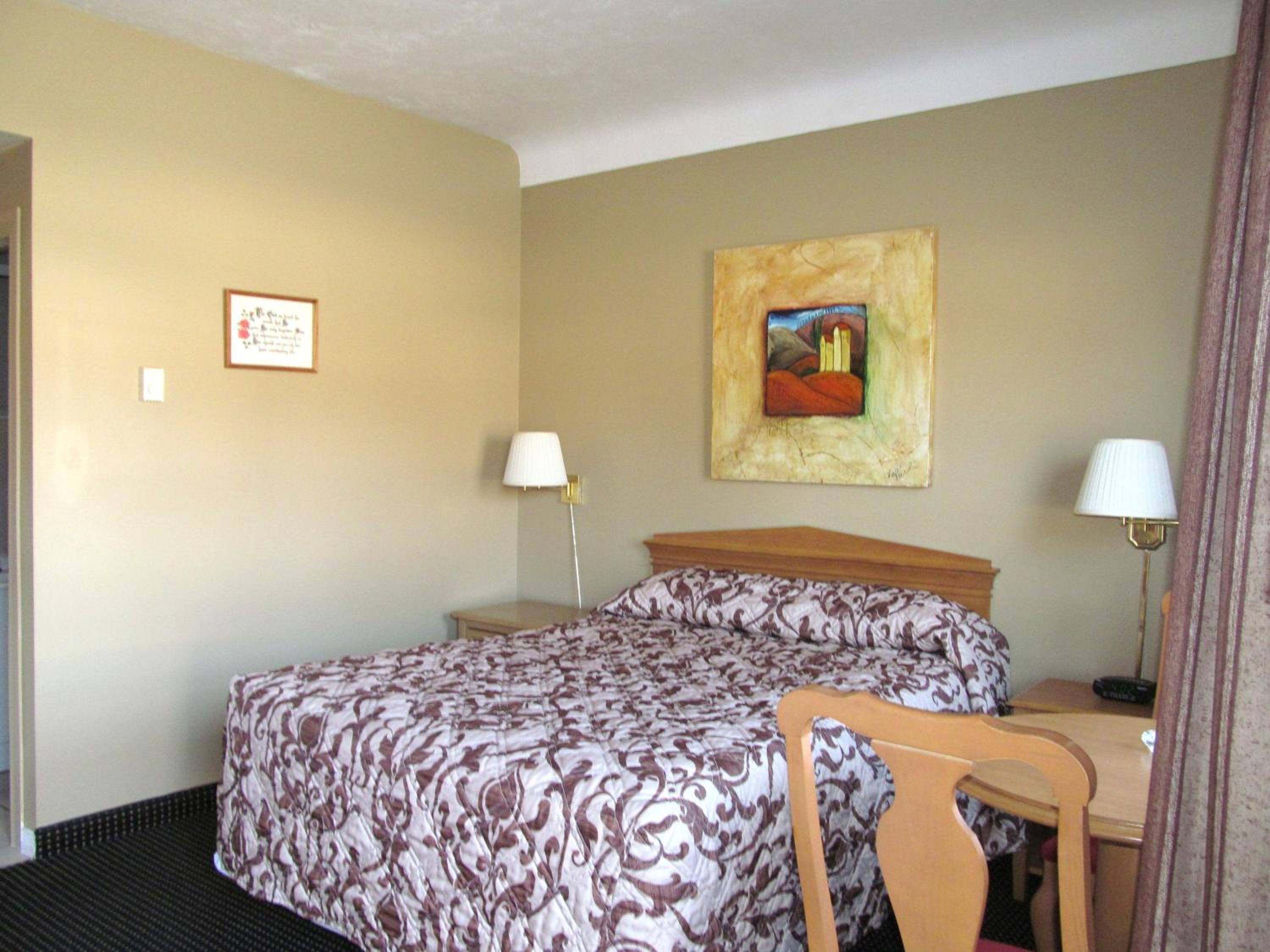 hotel room with a bed, desk, and chair