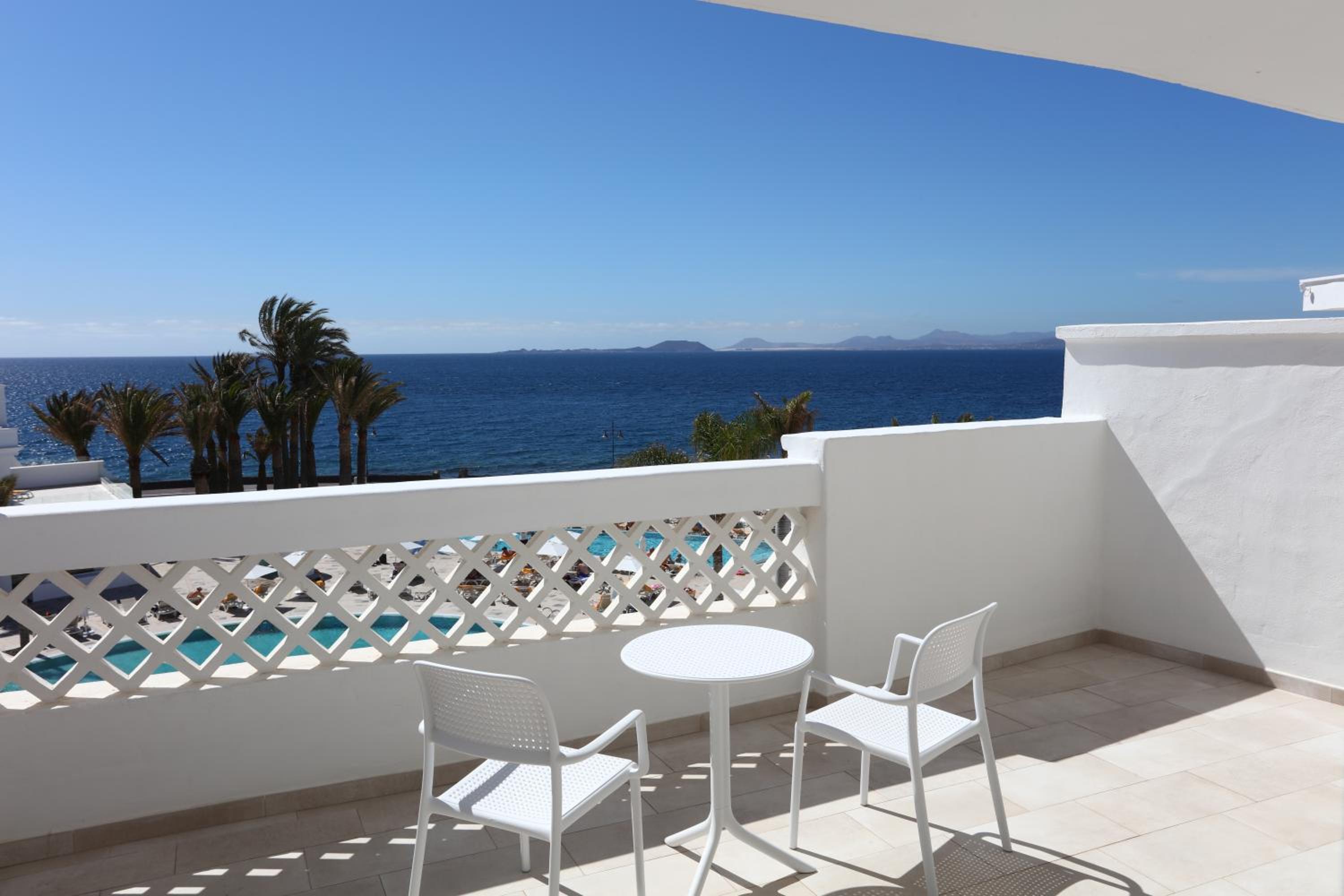 balcony with a table and two chairs overlooking the ocean