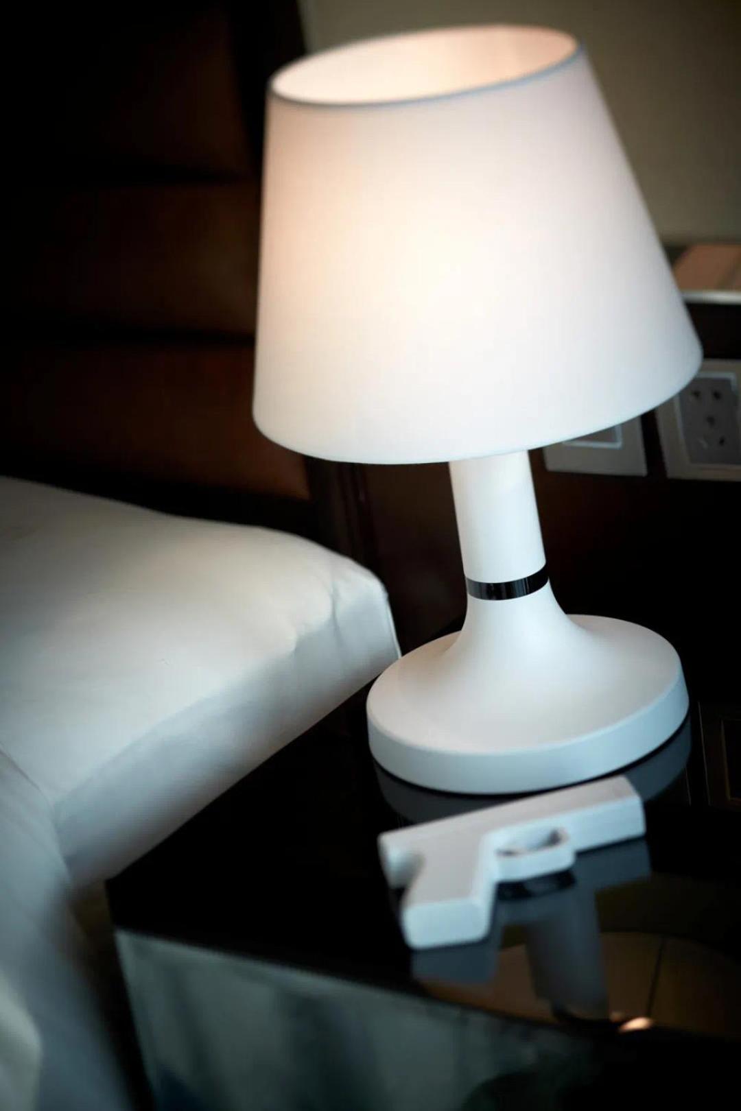 table with a lamp and a remote control on it