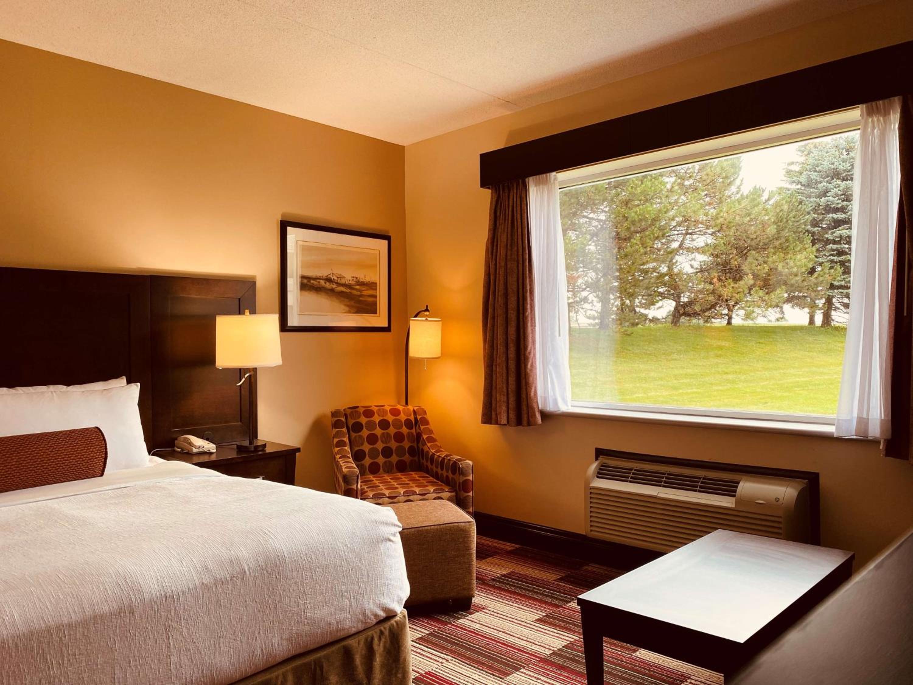 hotel room with a bed, chair, and air conditioner