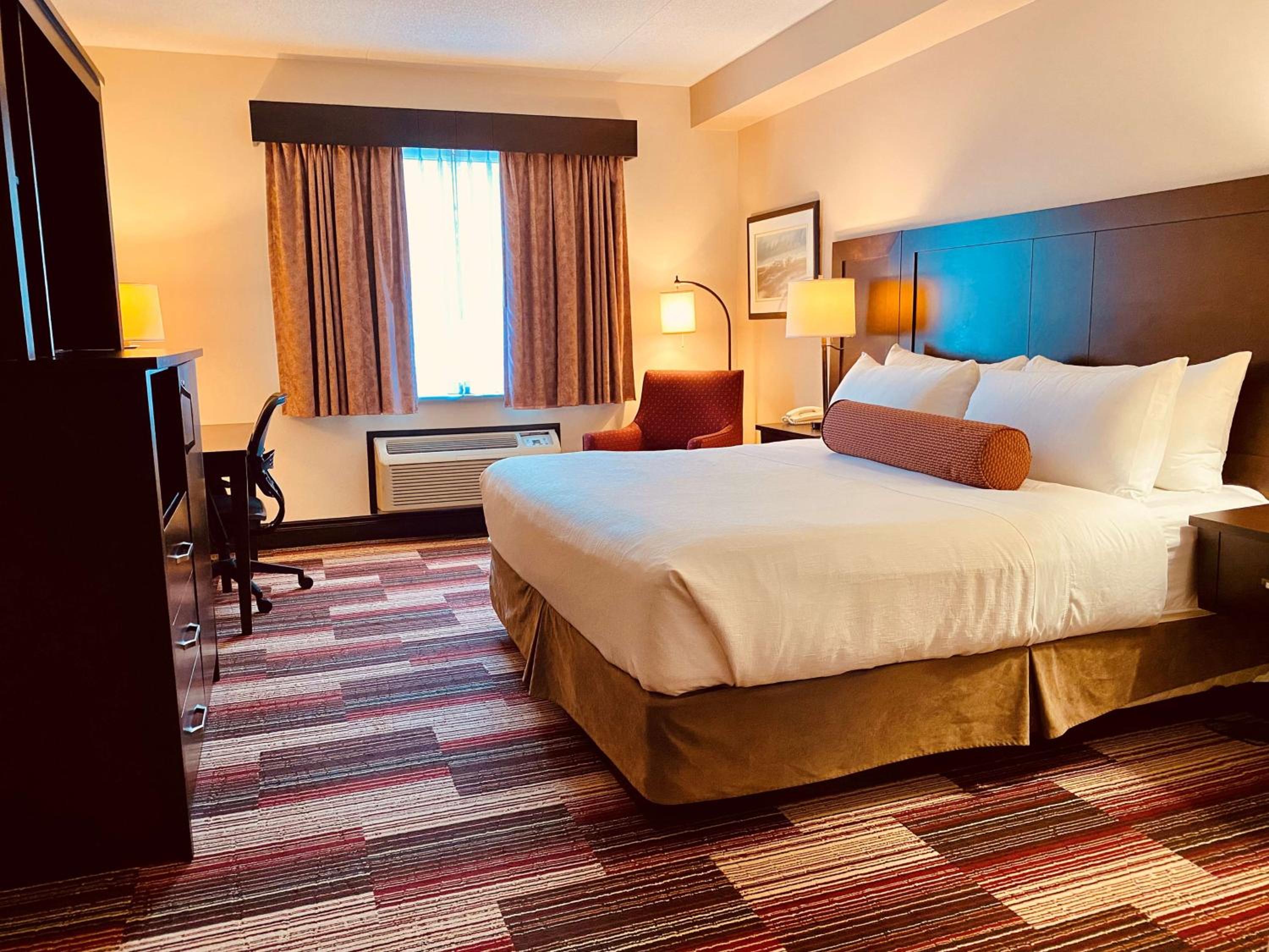 hotel room with a bed, desk, and television