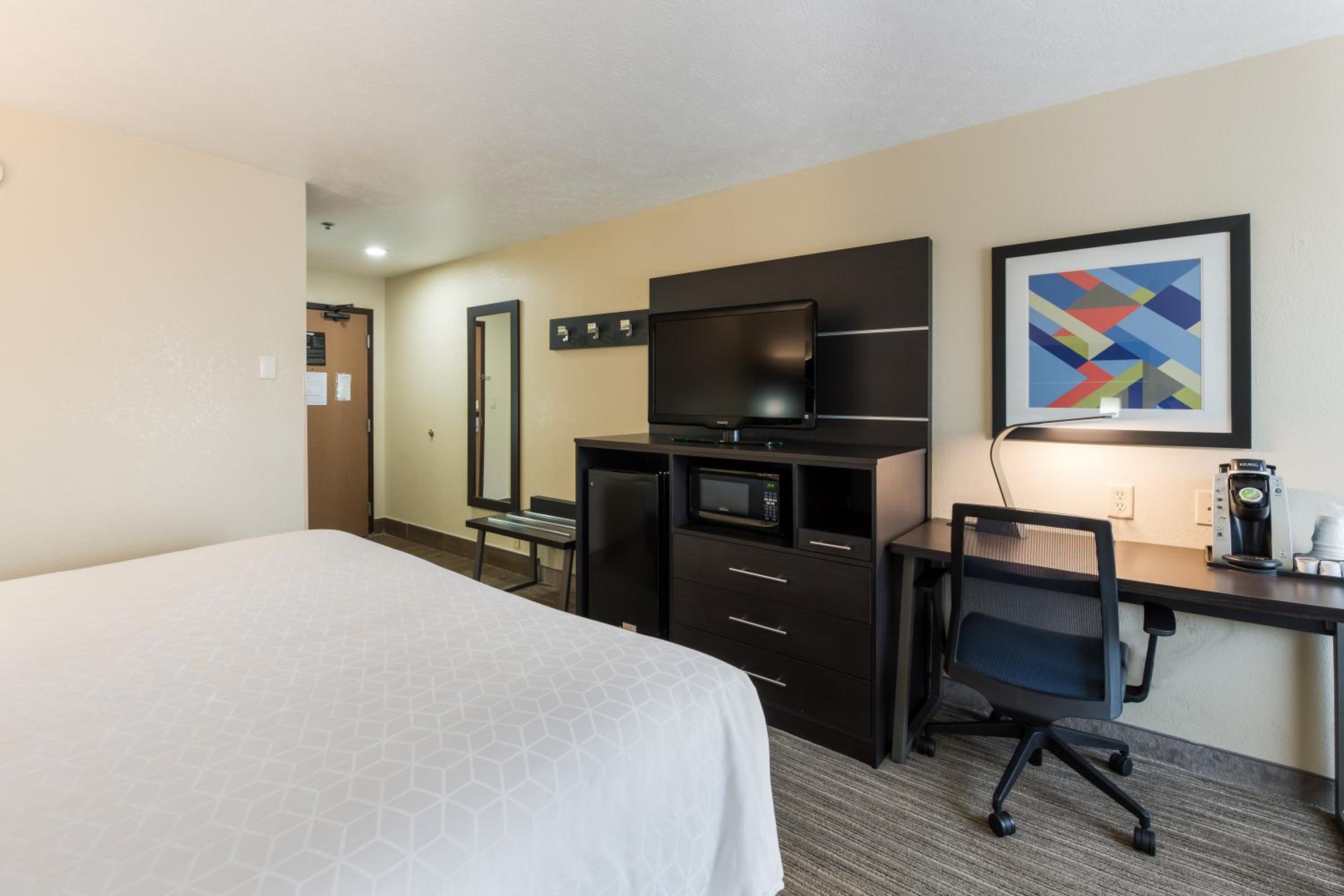hotel room with a bed, desk, and television